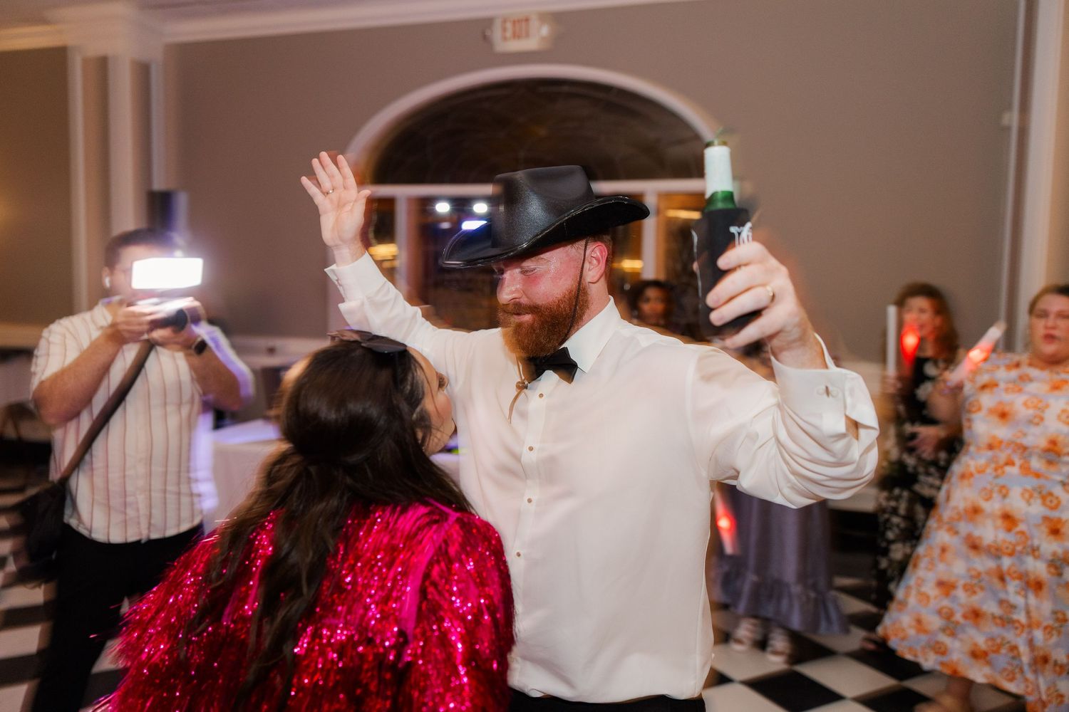 Lively dance party at wedding reception with guests in colorful attire.