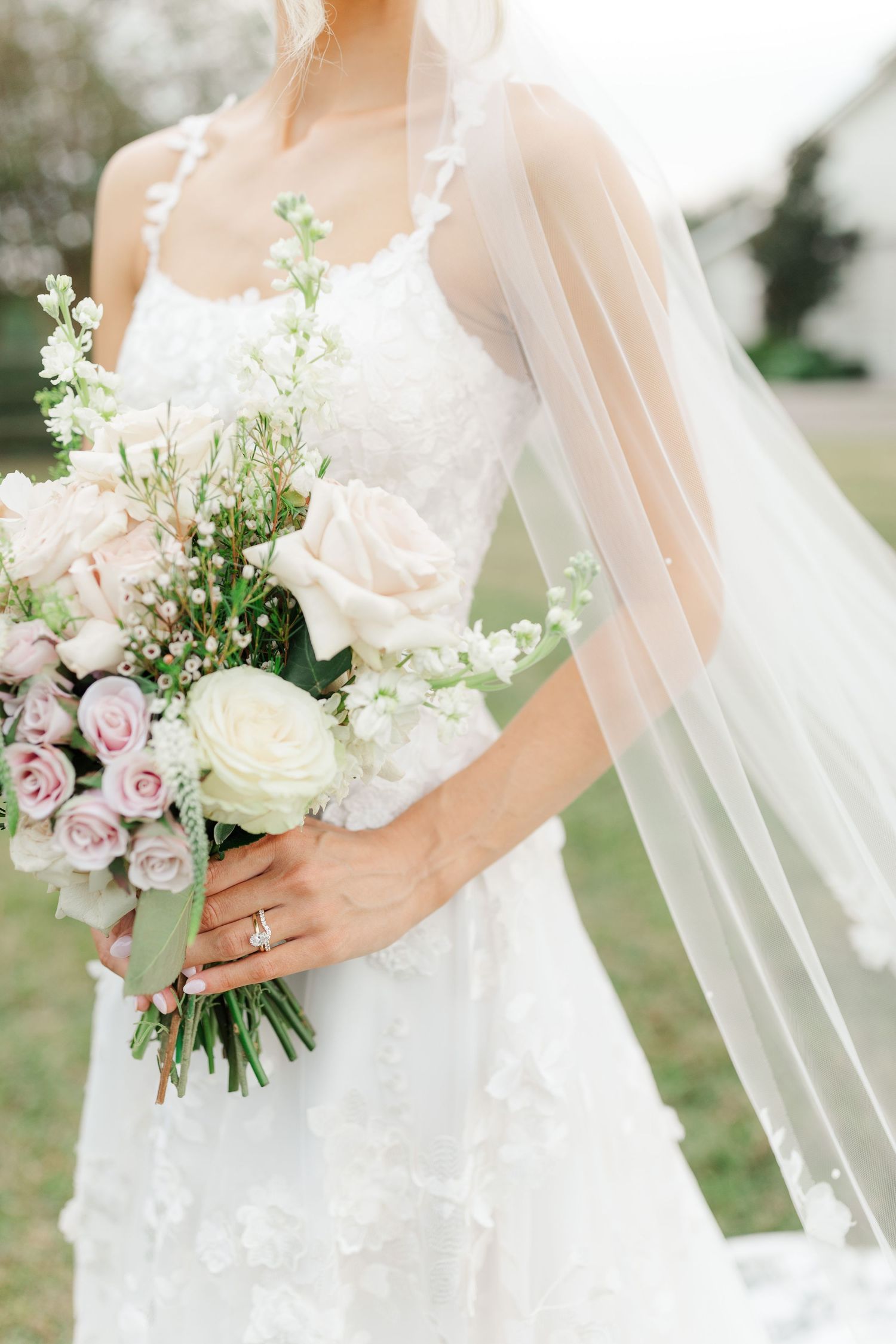 Delicate bridal bouquet with pink and white roses paired with a flowing veil.