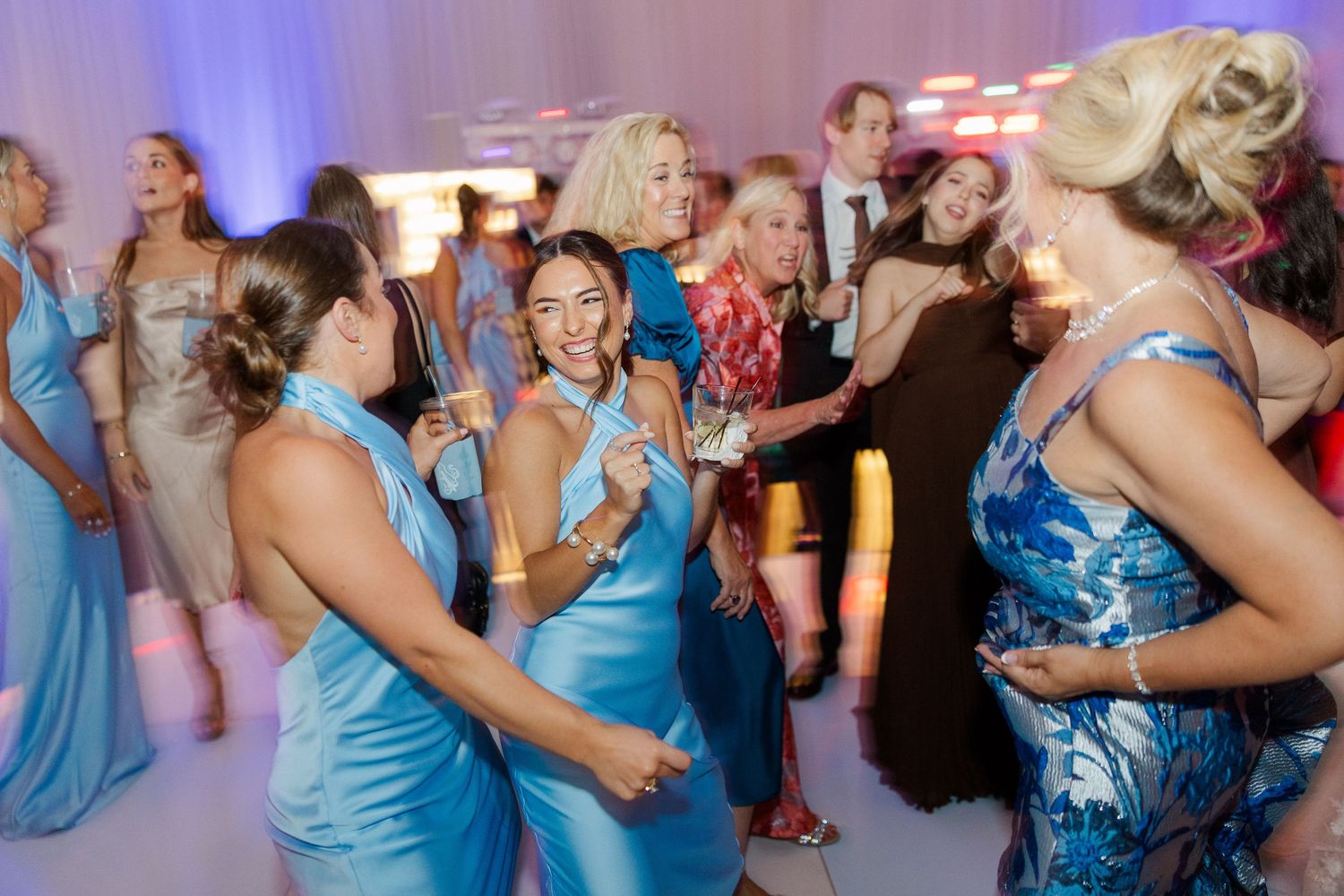 Lively dance floor scene with guests in blue dresses enjoying the wedding reception.