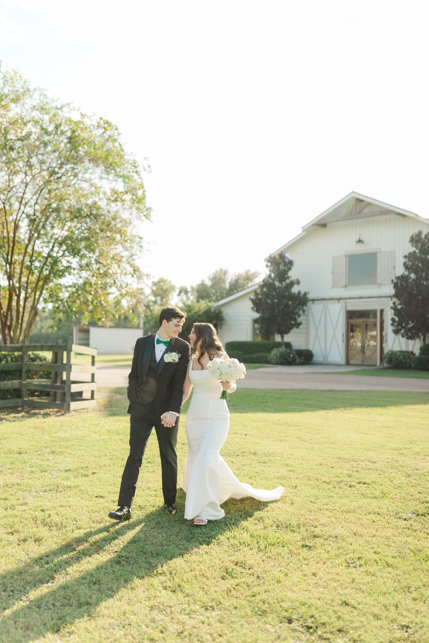 A rustic white barn creates a picturesque backdrop for a wedding celebration.