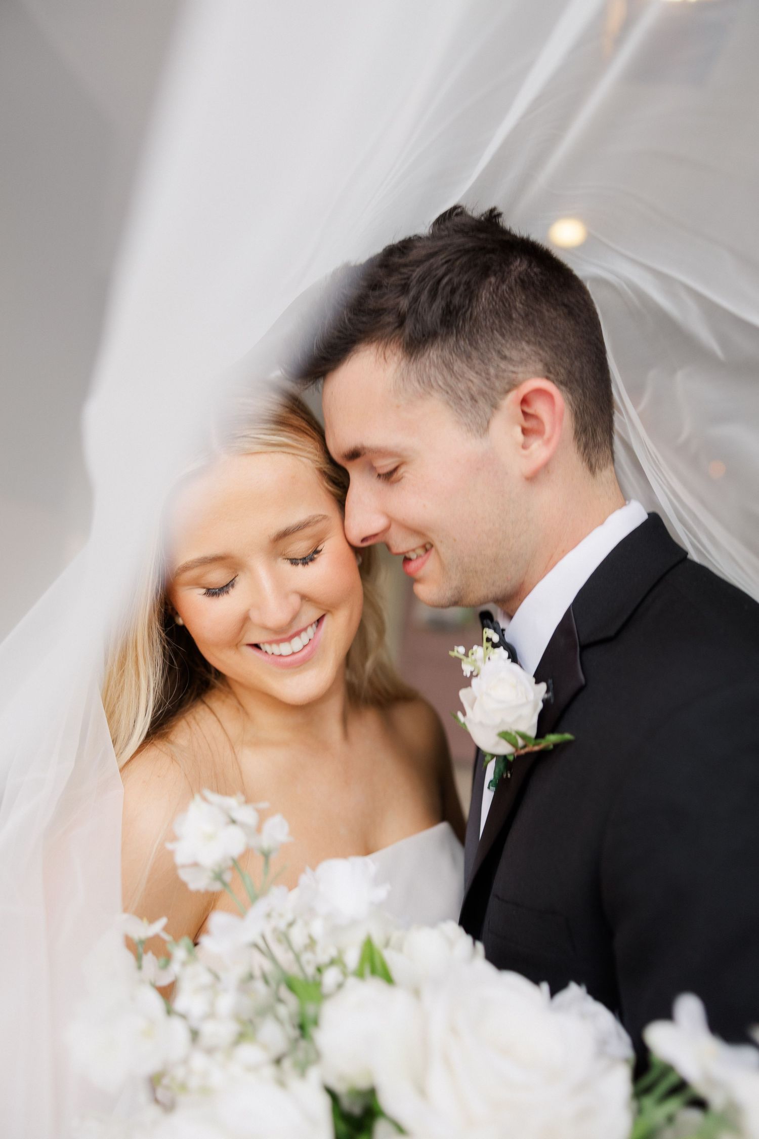 Intimate wedding portraits showing tender moments between newlyweds with white flowers.