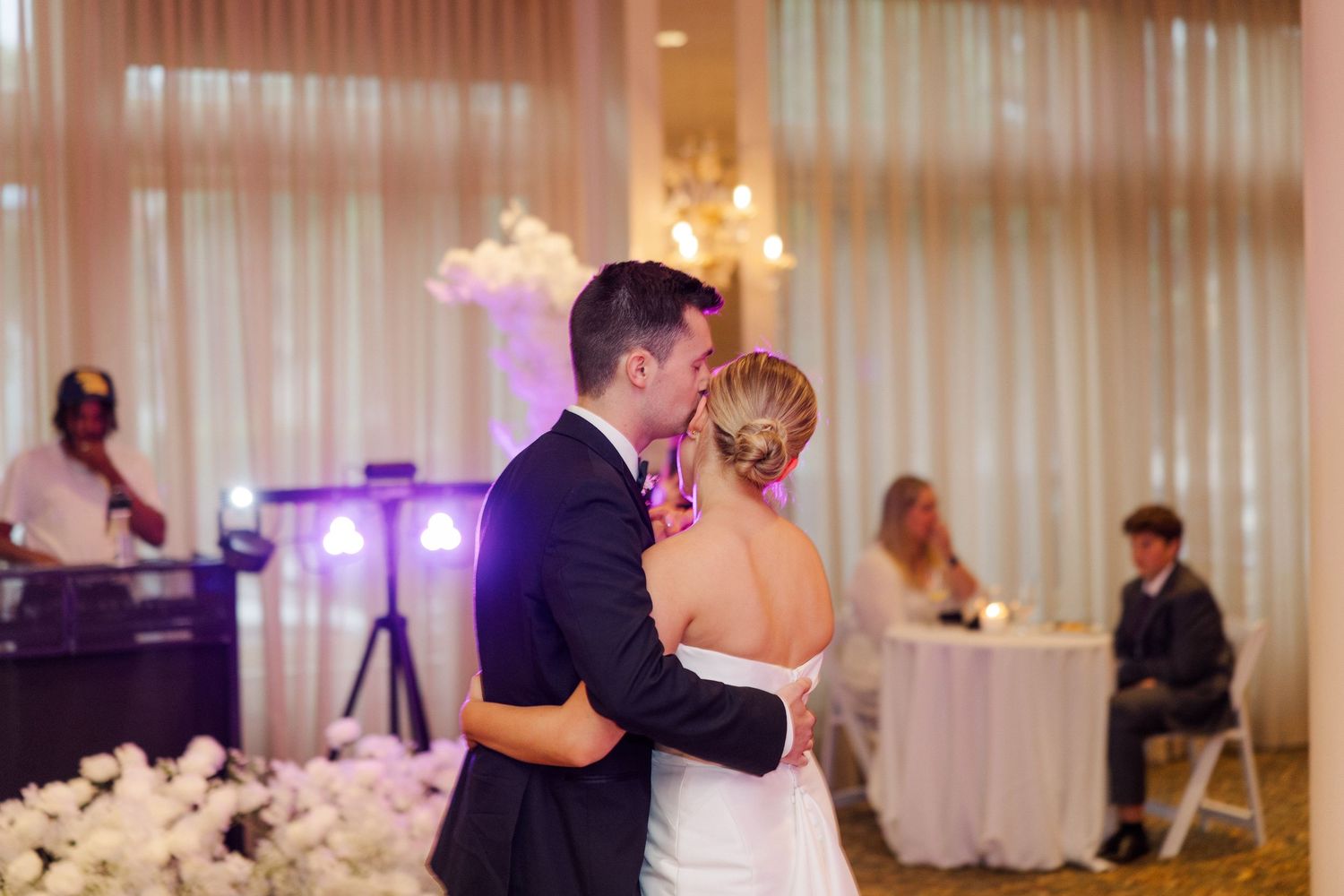 Romantic first dance at wedding reception with soft lighting and white drapes.