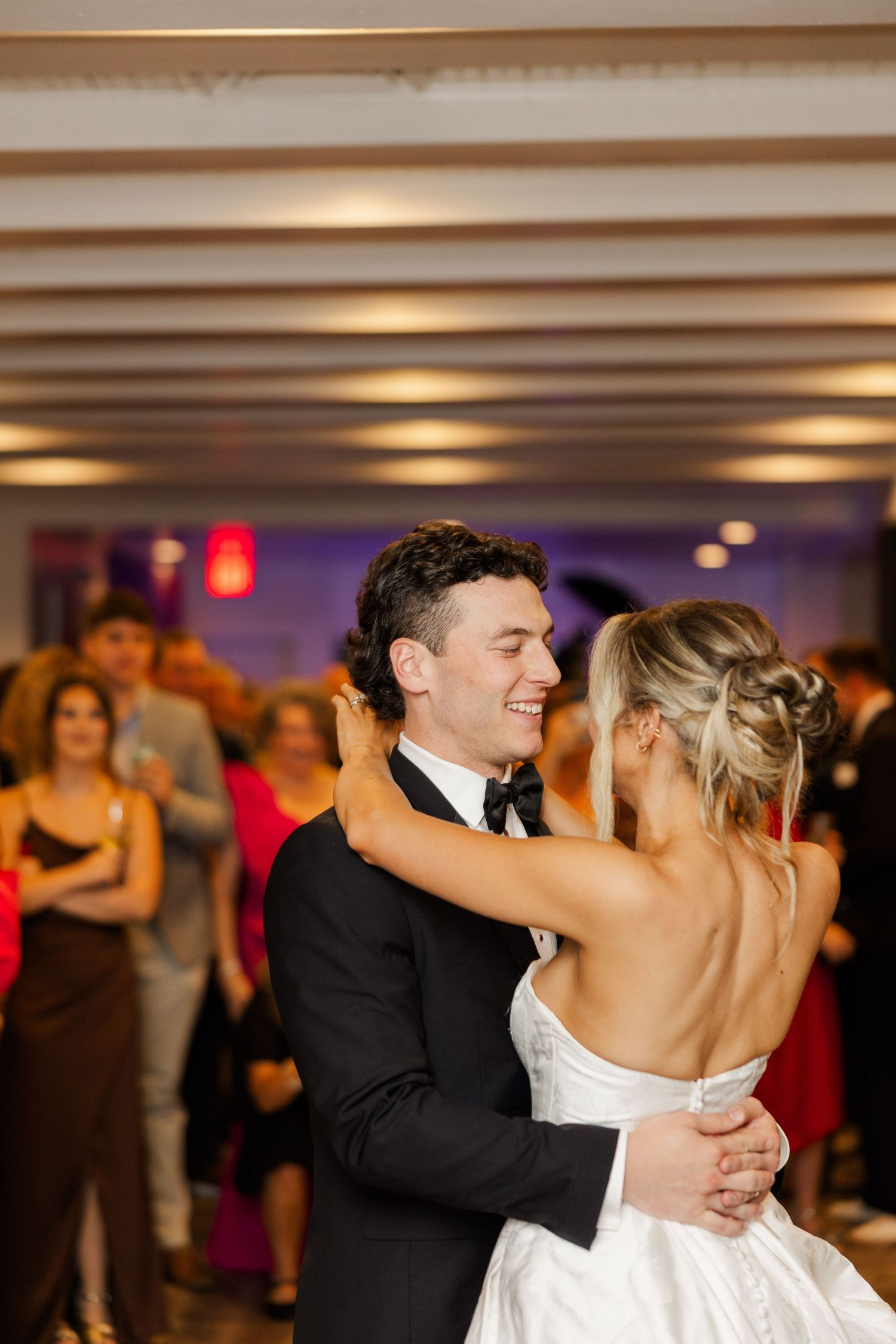 A couple shares their first dance at their wedding reception under dimmed lighting.