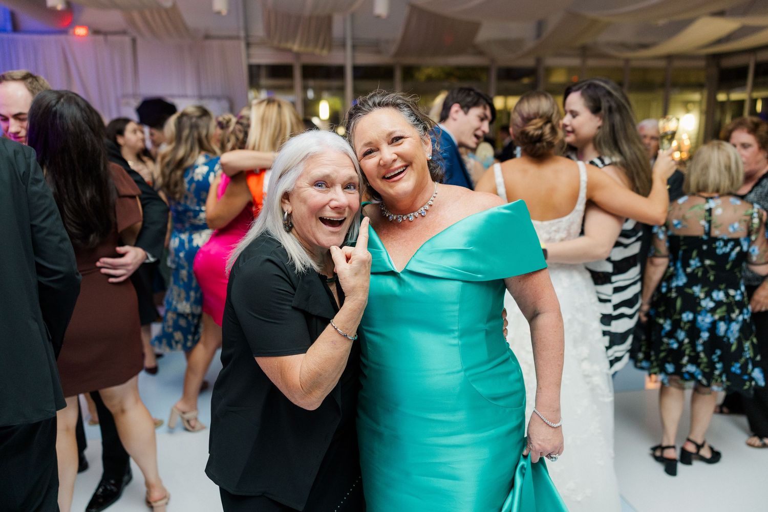 Wedding guests in colorful dresses sharing a joyful moment on the dance floor.