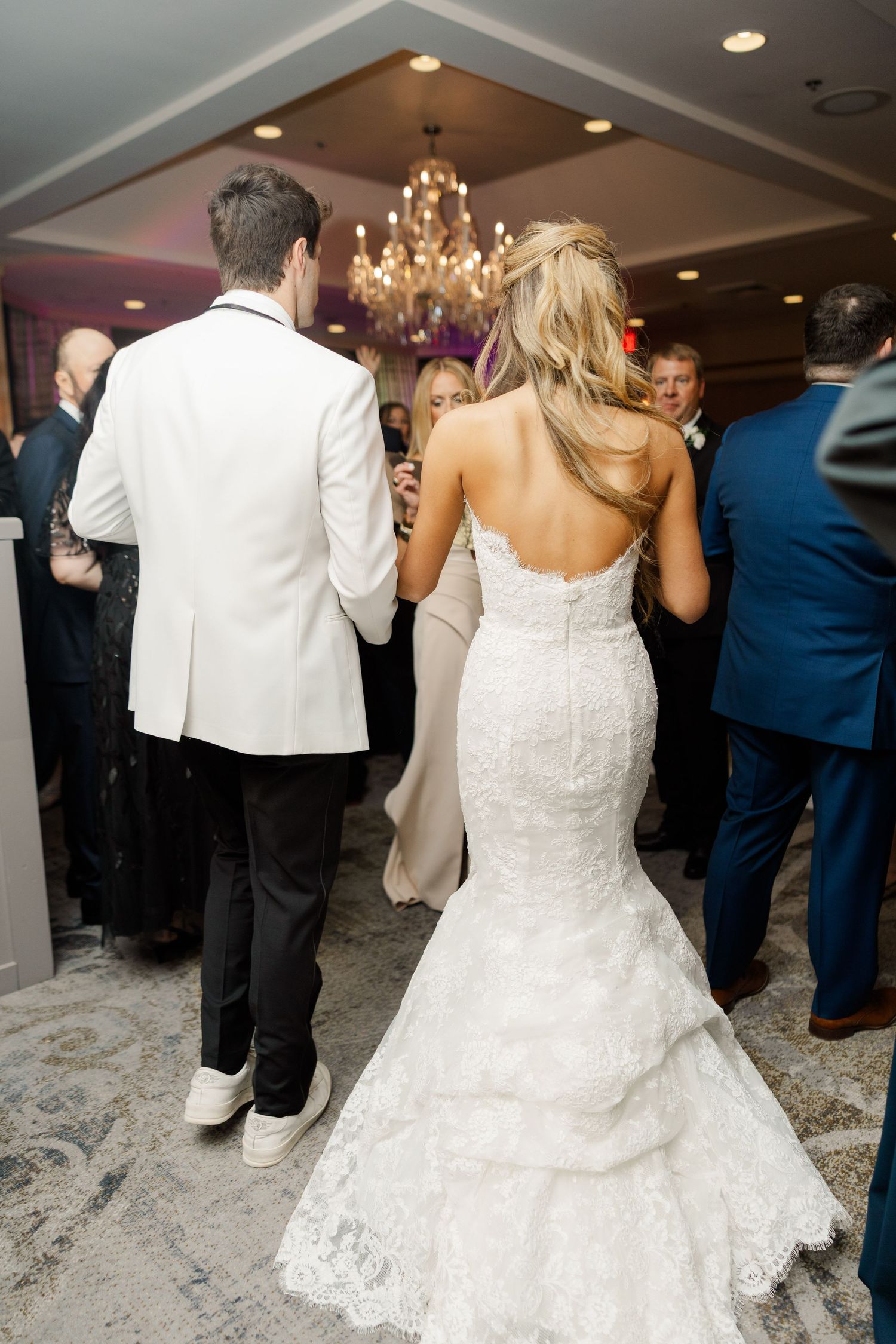 Wedding reception dance floor with bride in lace gown surrounded by guests.