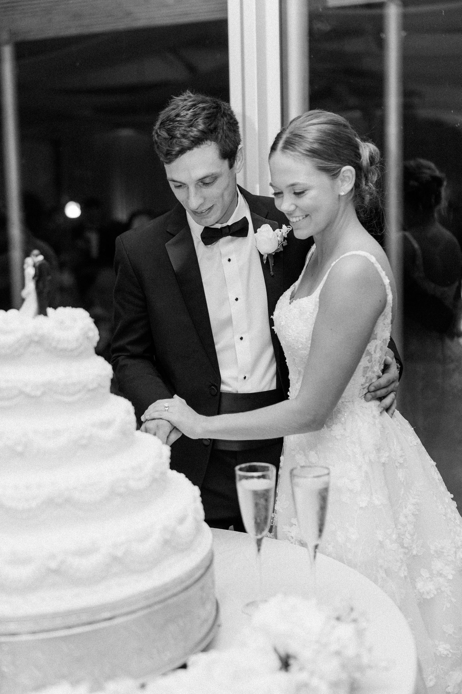 Black and white wedding photo sequence showing newlyweds cutting their elegant white tiered cake together at reception.