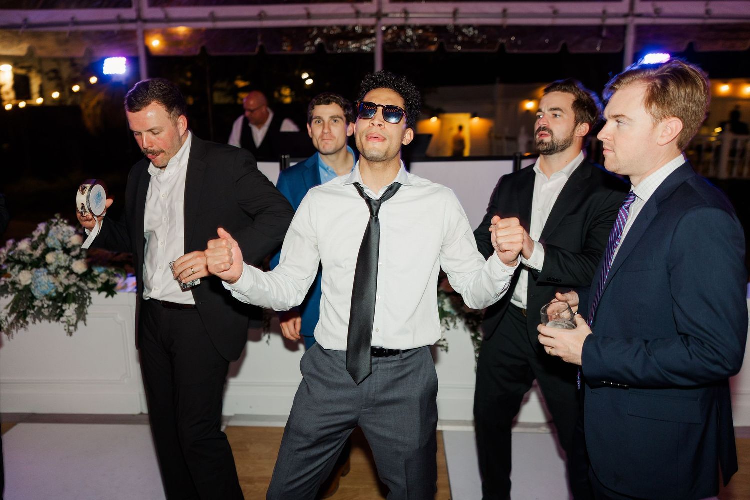 Wedding party dancing and celebrating at nighttime reception.