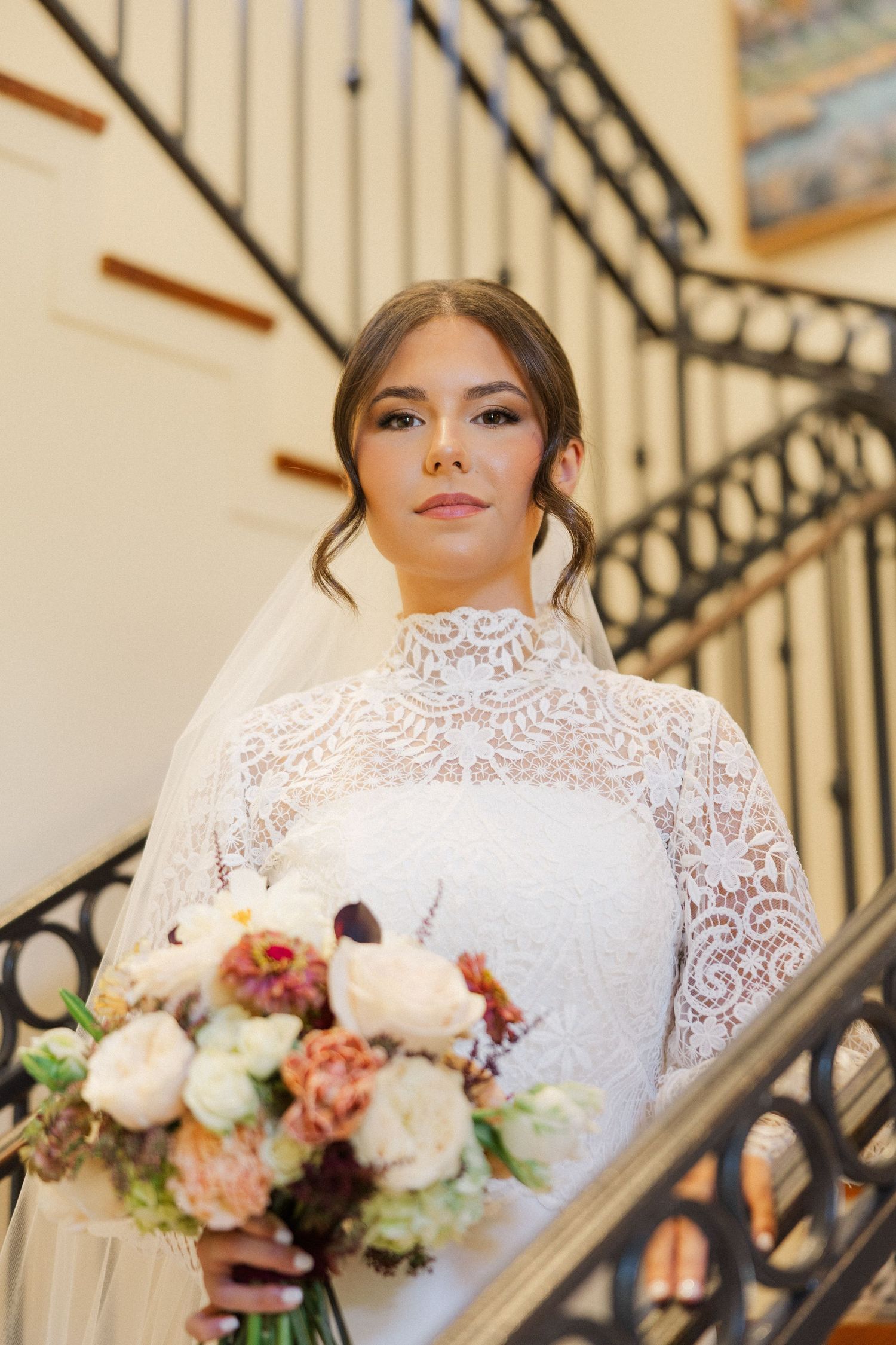 Close-up bridal portraits featuring delicate lace neckline details and romantic bouquet against ornate railing.