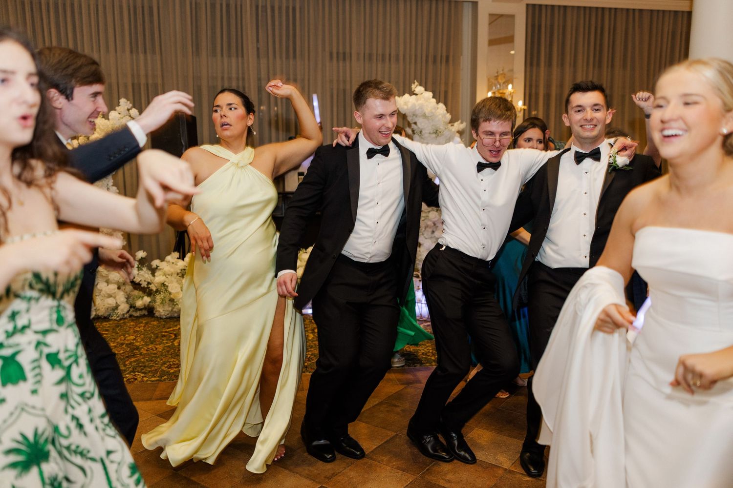 Wedding guests dance and celebrate on a wooden dance floor during the reception.