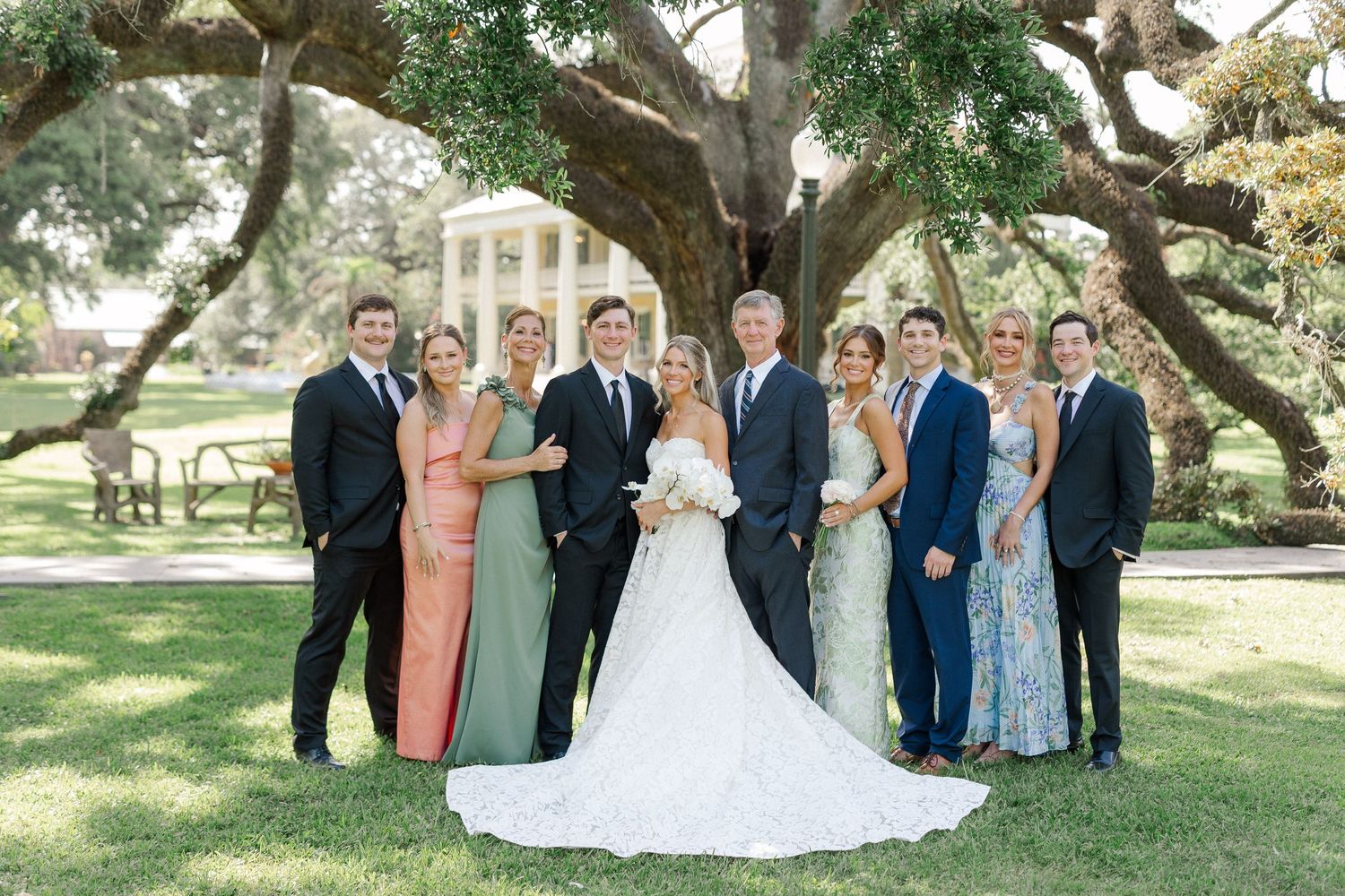 Family portrait with bride and groom under majestic oak tree at classic Southern plantation.