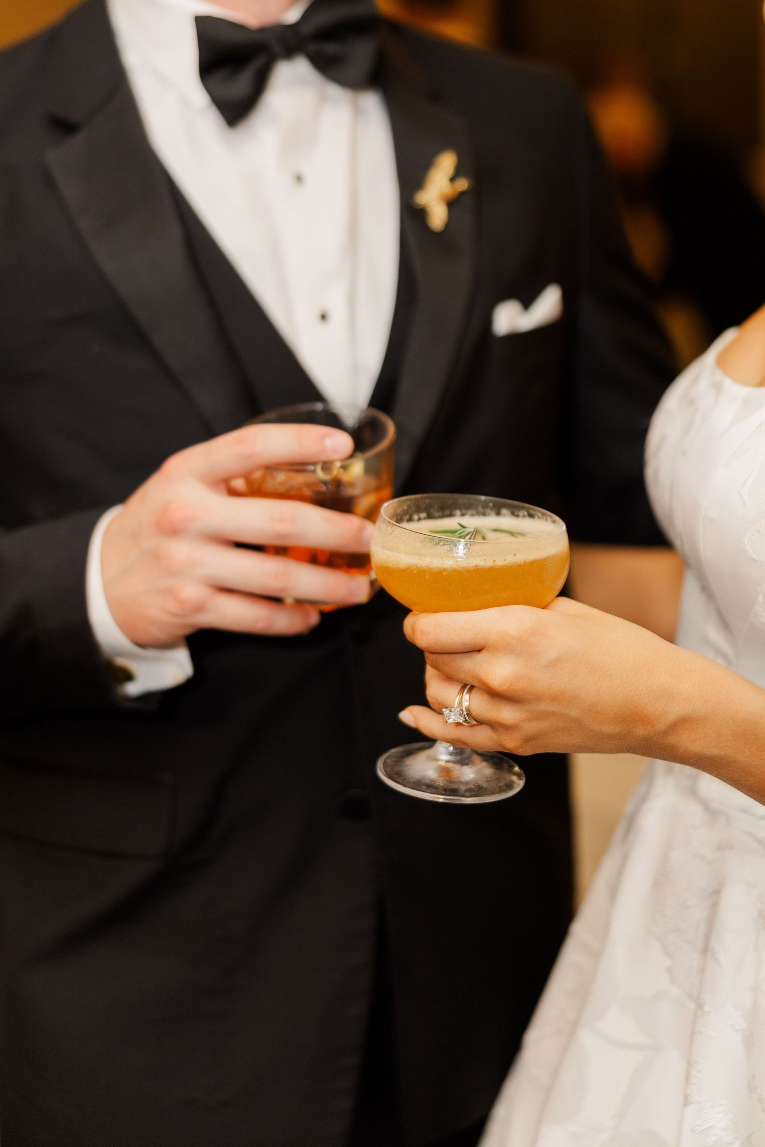 Elegant cocktails being passed between hands at a formal wedding reception.