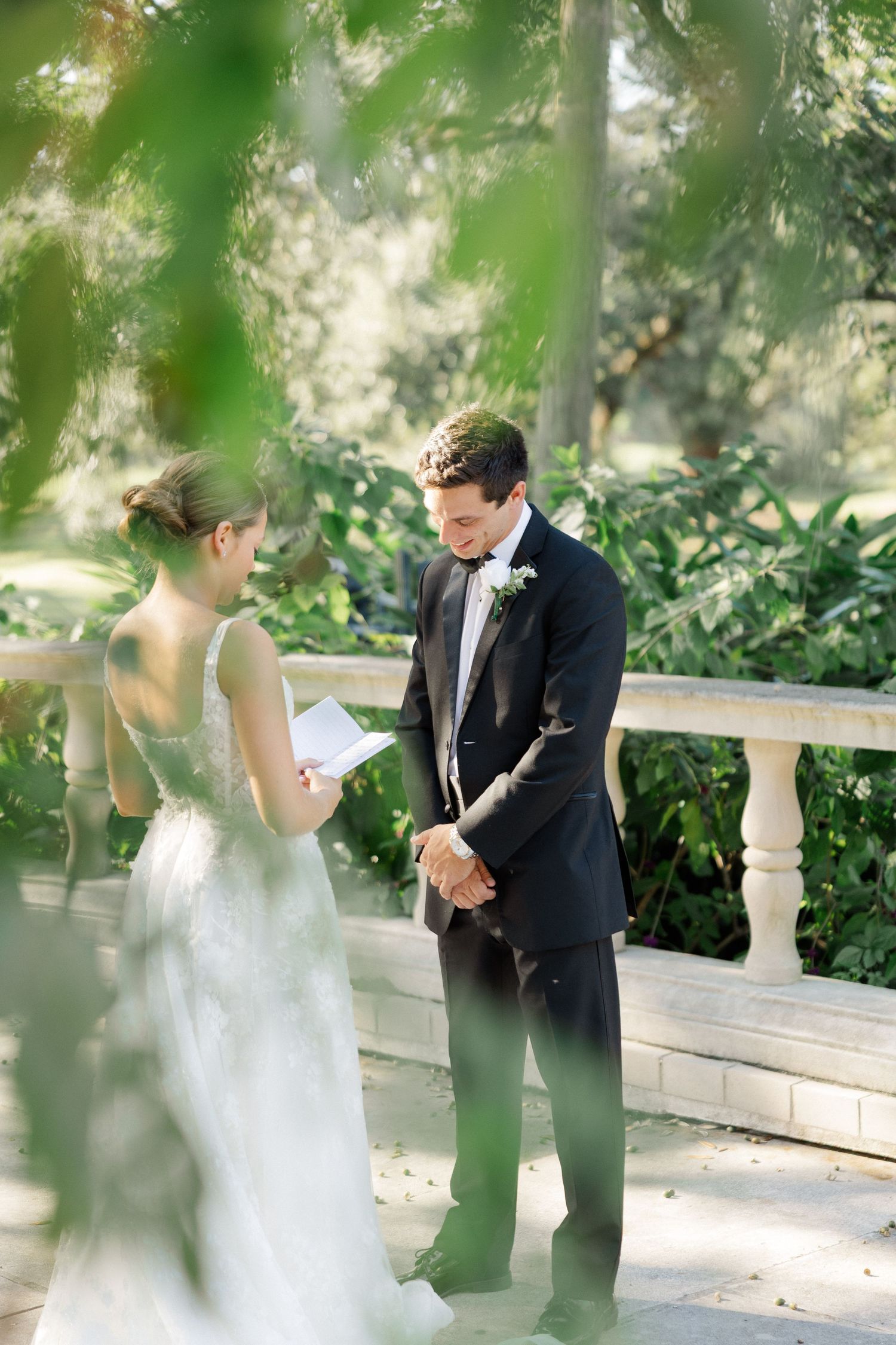 Couple sharing a private moment in a garden setting through green foliage.
