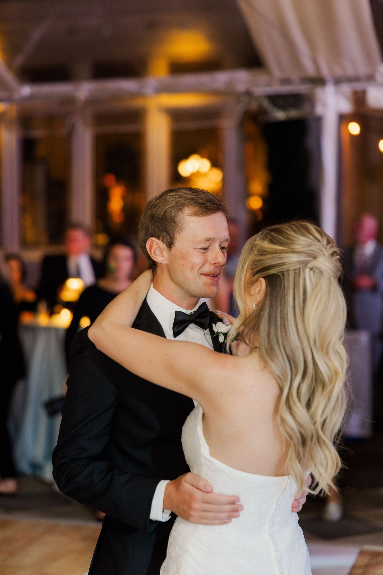 A couple shares their first dance at an elegantly lit wedding reception.