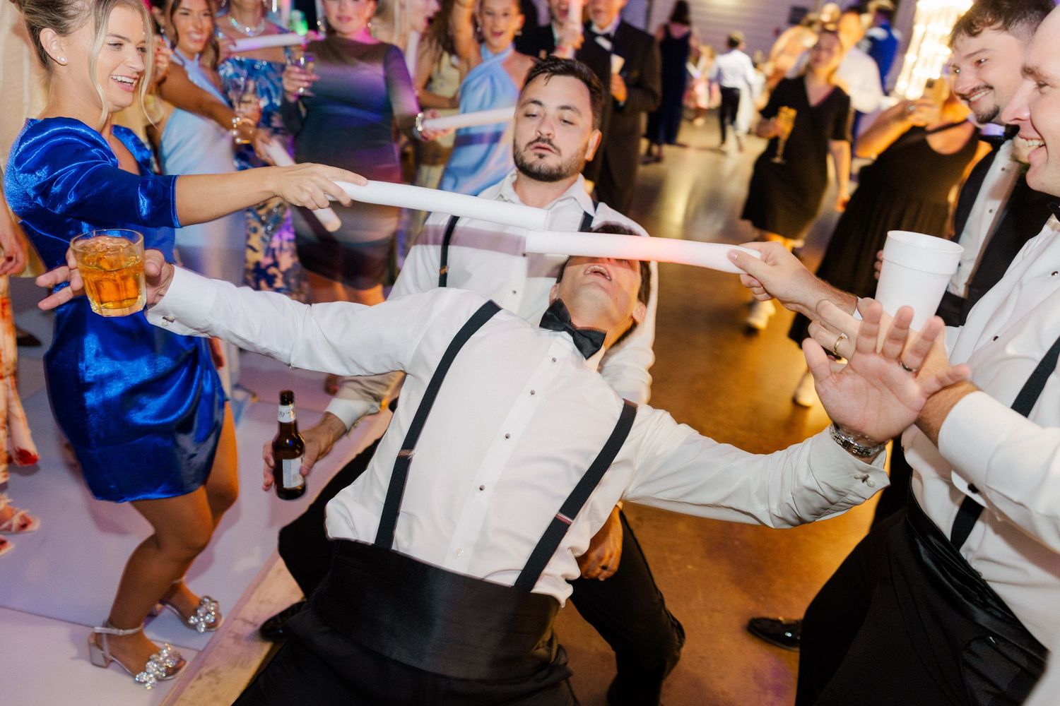 Wedding reception dance party with guests in formal attire dancing energetically on the dance floor.