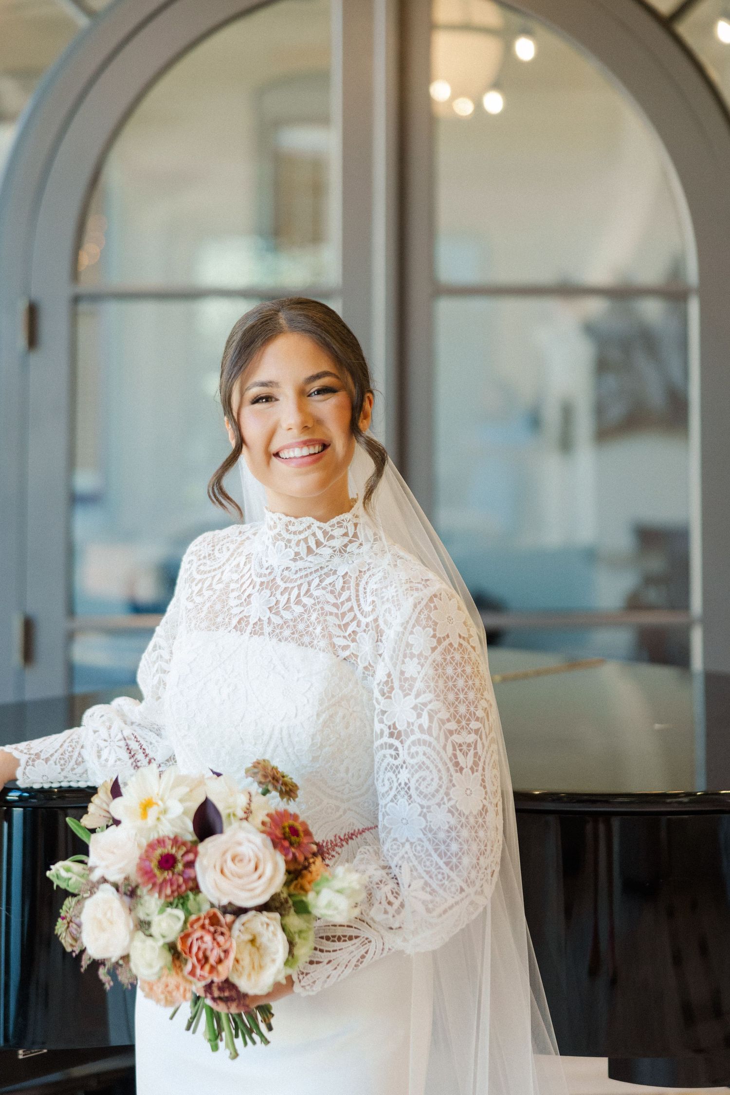Elegant bridal portraits in an arched window setting featuring a detailed lace gown and romantic bouquet.
