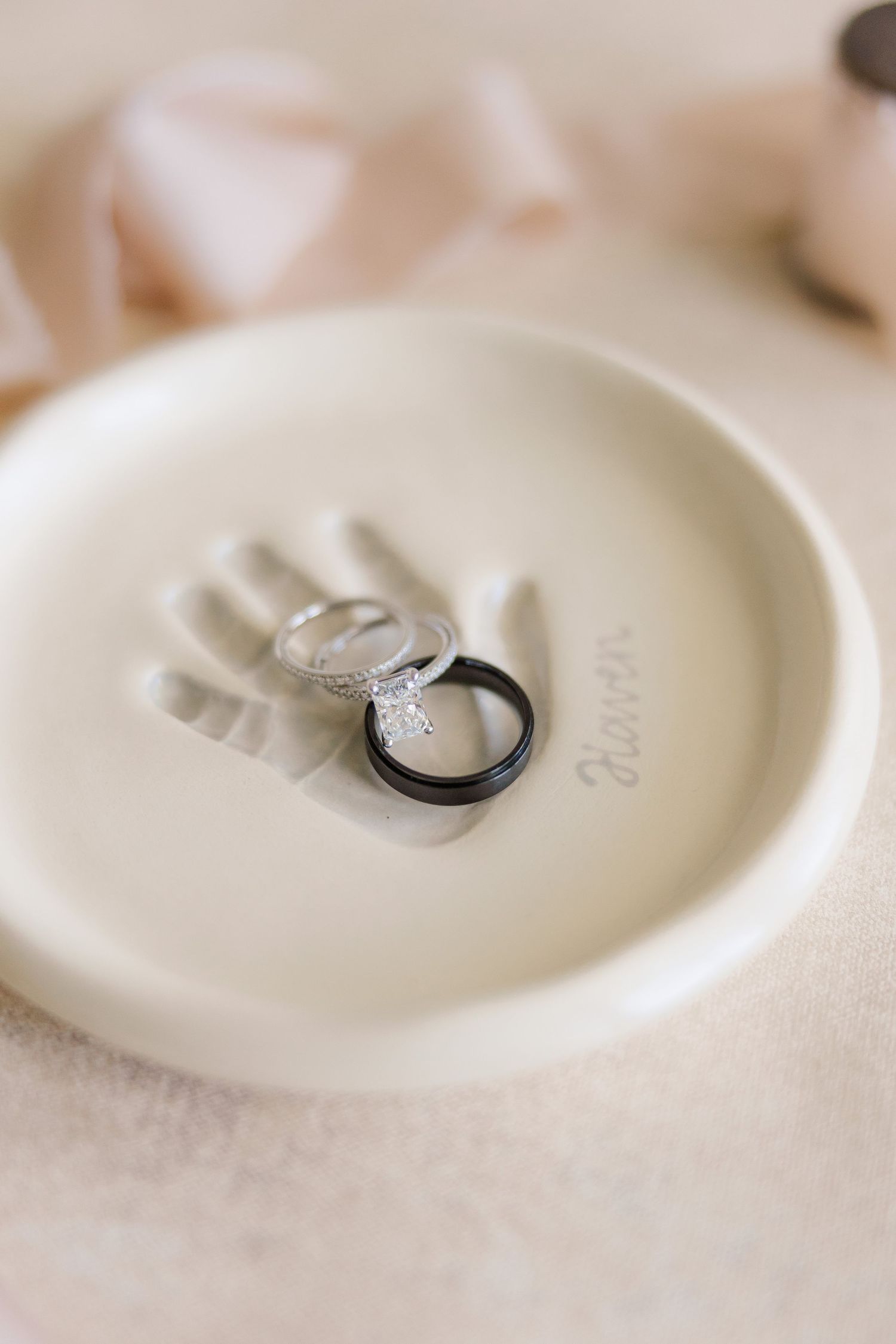 Wedding rings resting on a small white ceramic dish with delicate details.