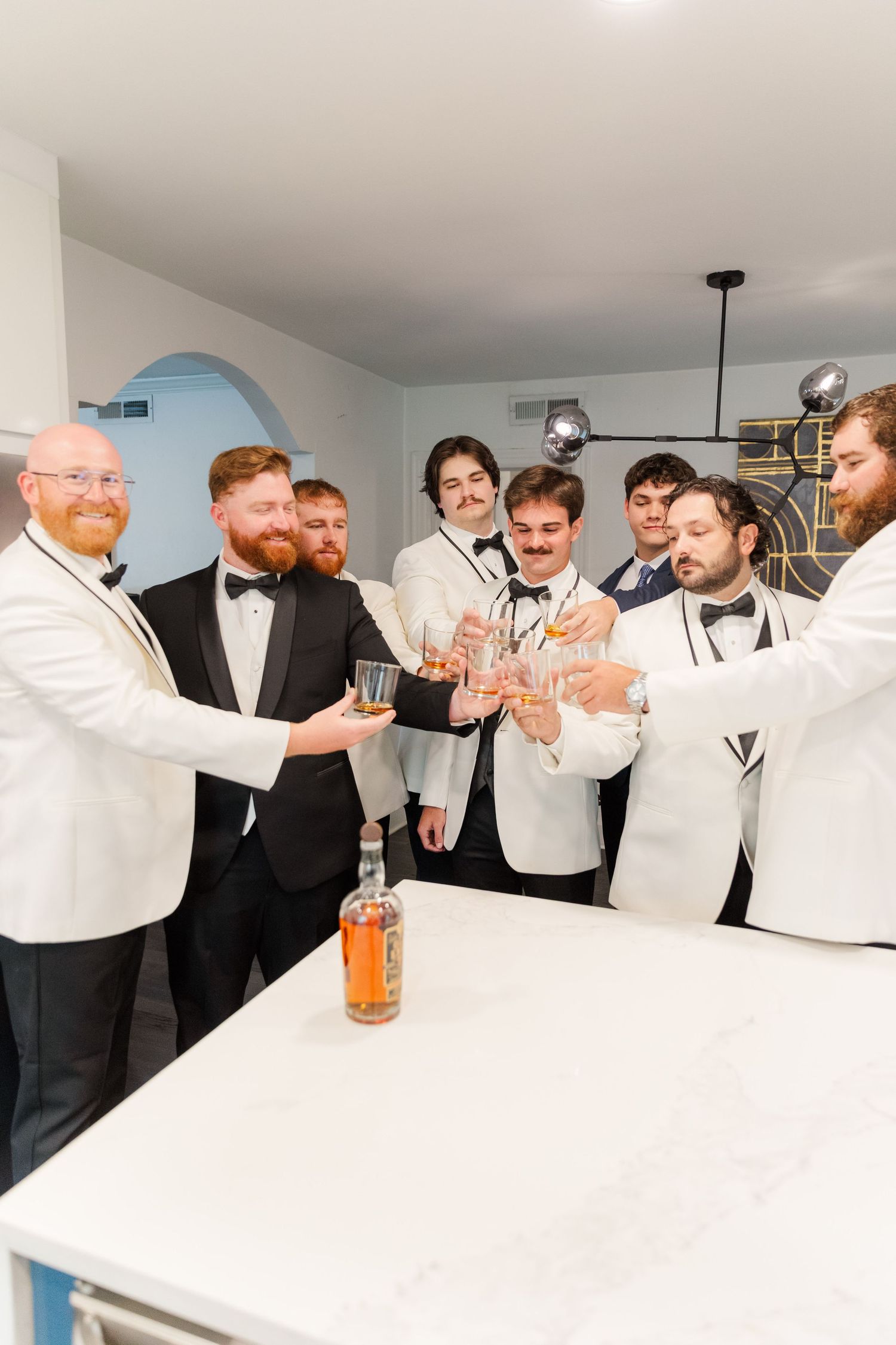 Groomsmen in formal attire toasting and celebrating at a wedding reception.