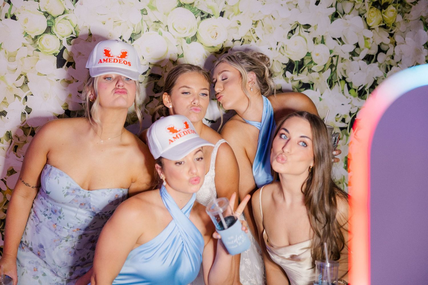 Group of wedding guests posing together in a photo booth with floral backdrop.