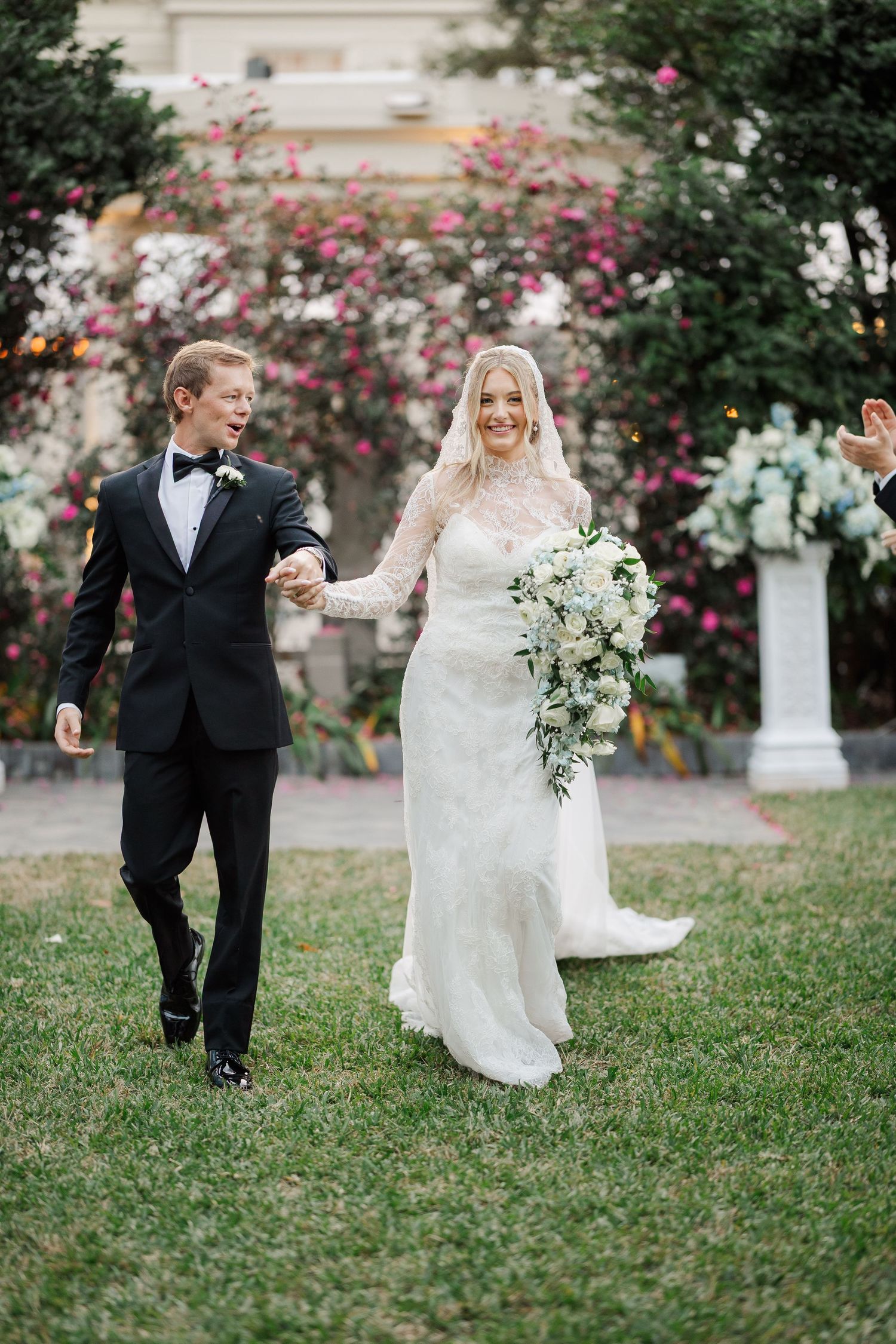 A couple playfully runs through a garden setting during their wedding celebration.