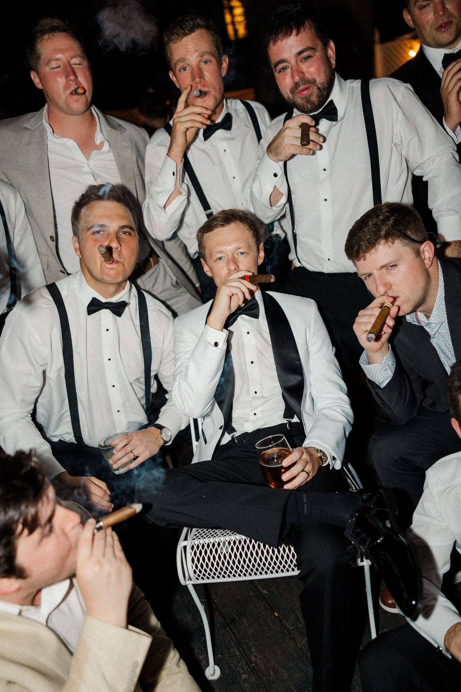 Groomsmen in formal attire enjoying candid moments at a wedding reception.