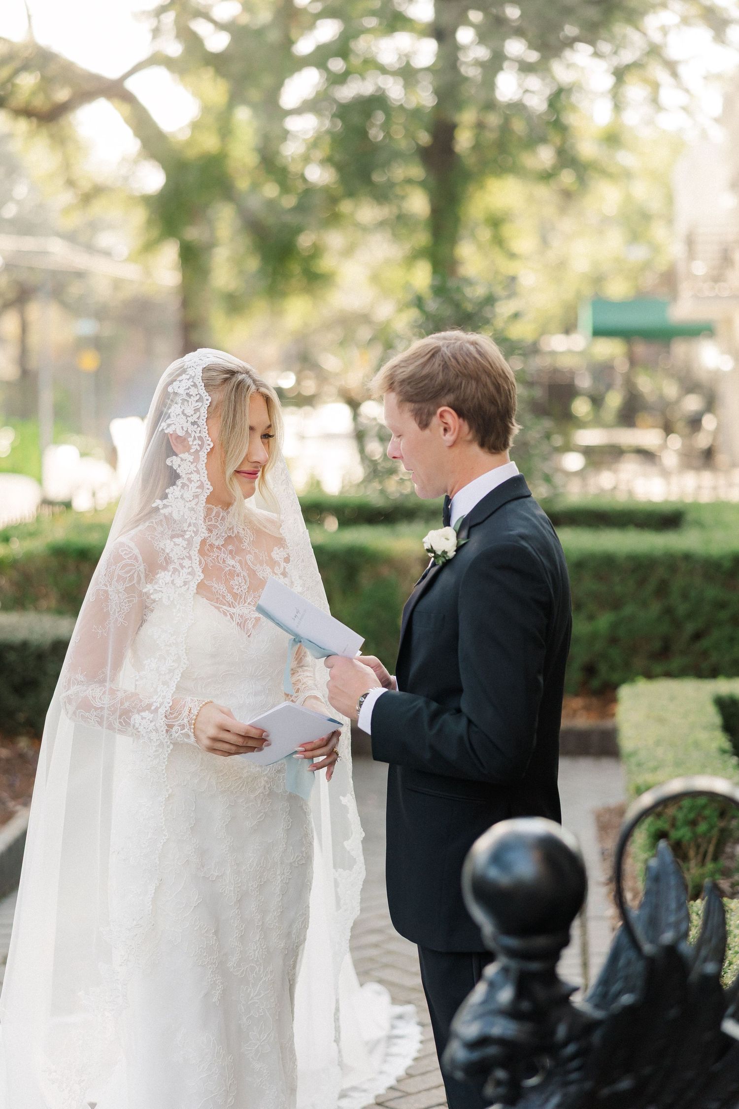 Elegant outdoor wedding ceremony with couple exchanging vows under a lace veil.