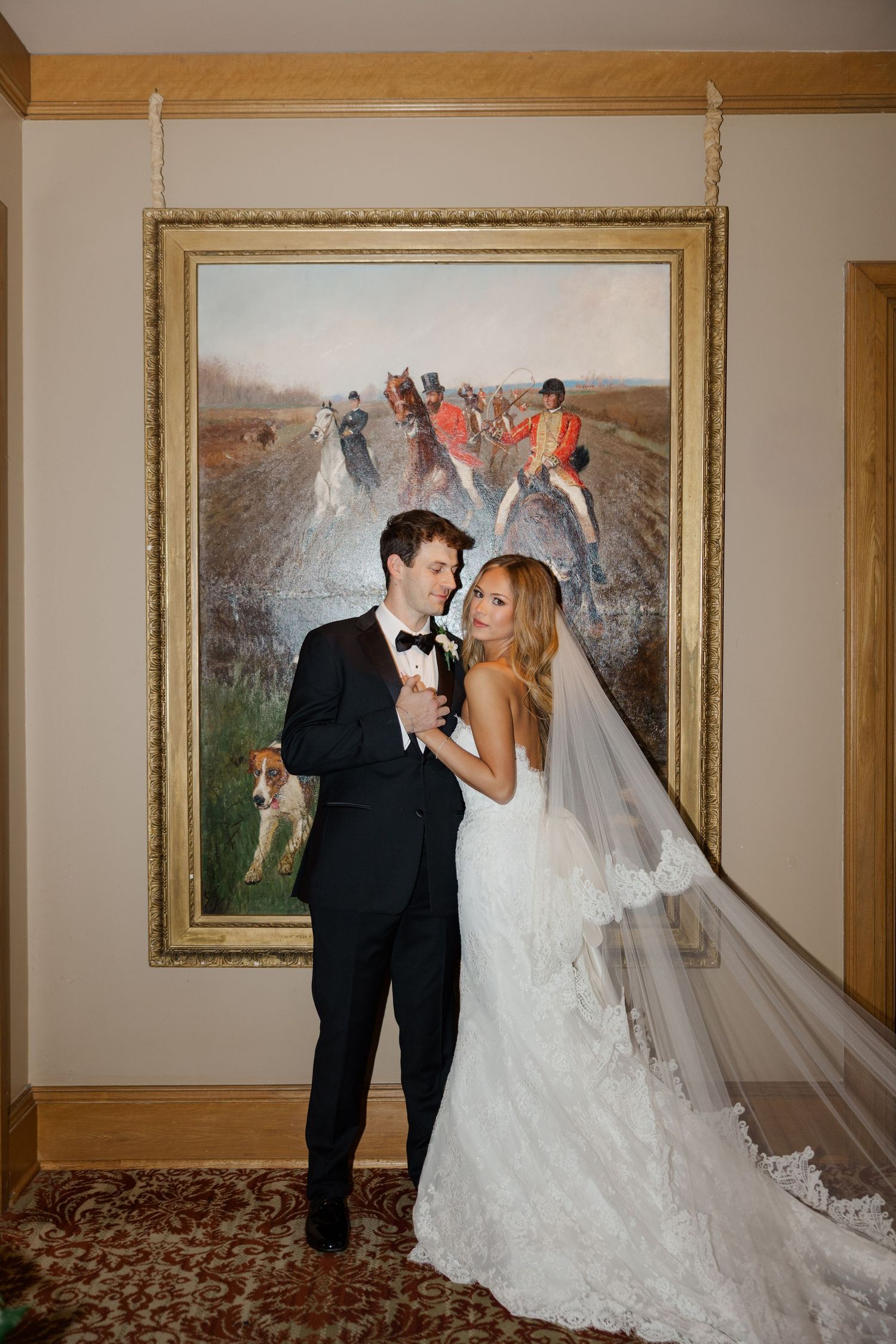 Romantic wedding portraits displayed in ornate gold frames along hallway wall.