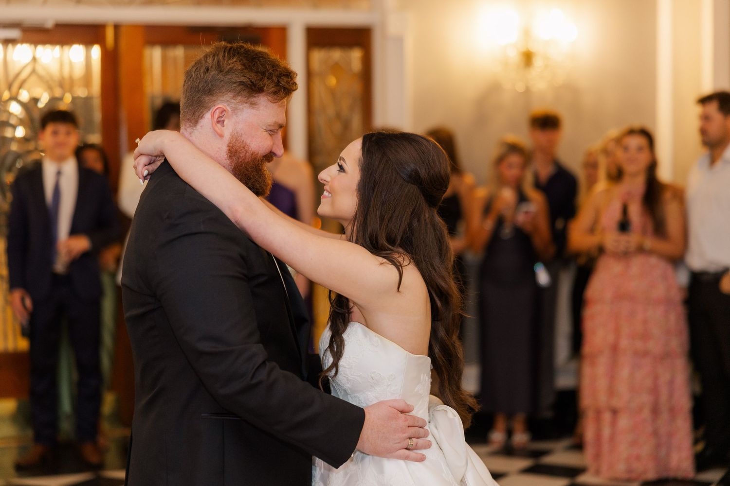 Couples dancing together at elegant wedding reception with warm lighting.