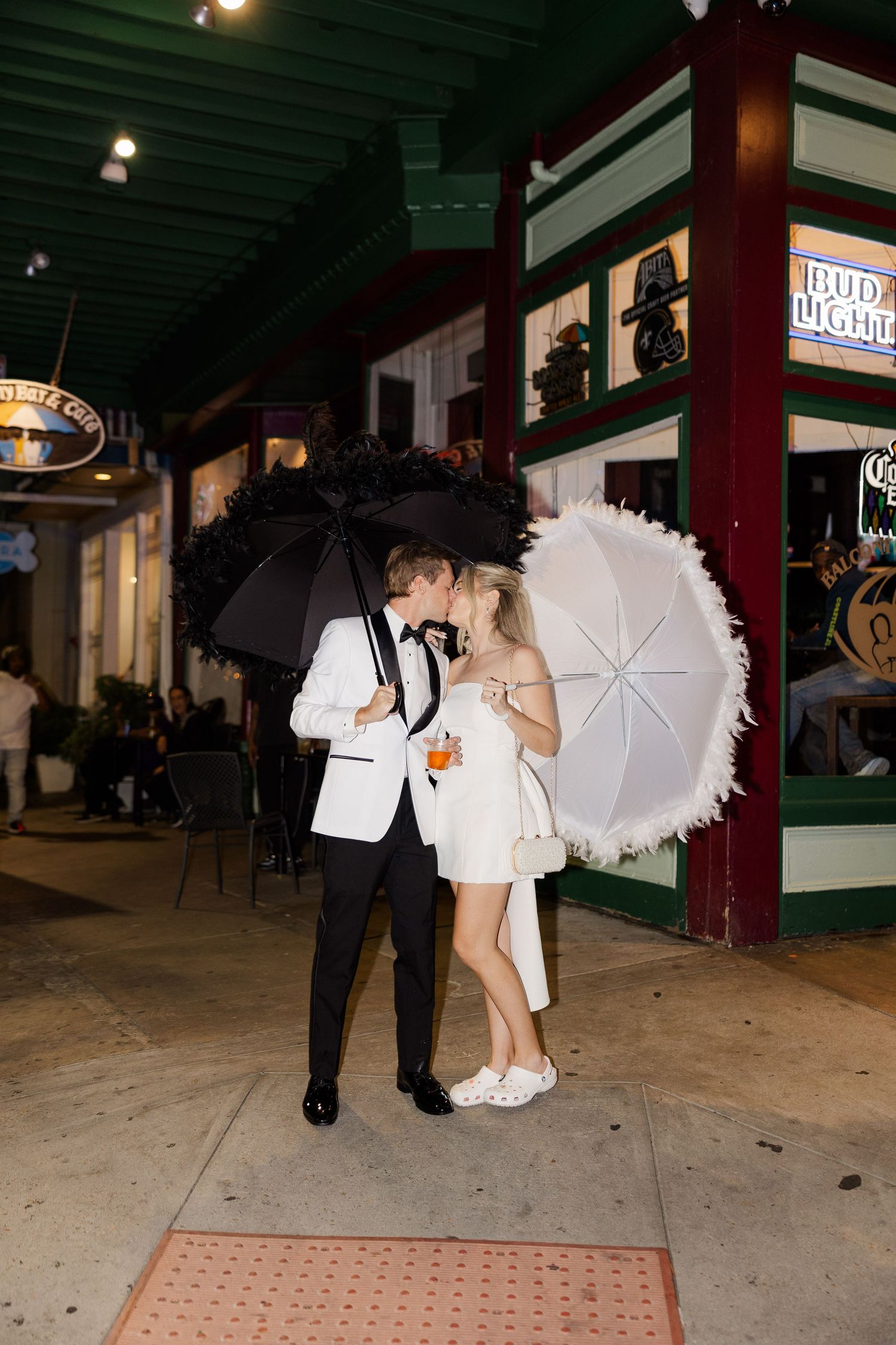Wedding couple with parasol walking outside venue at night.