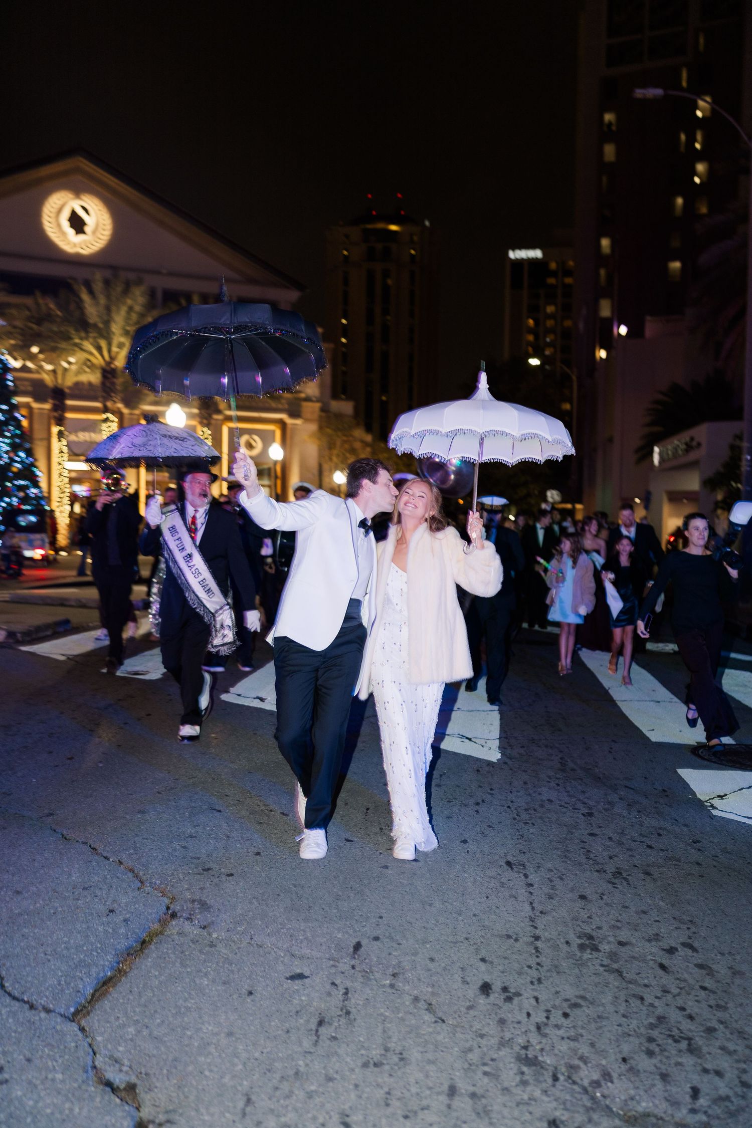 Couple walking with illuminated parasols at night in an urban setting.
