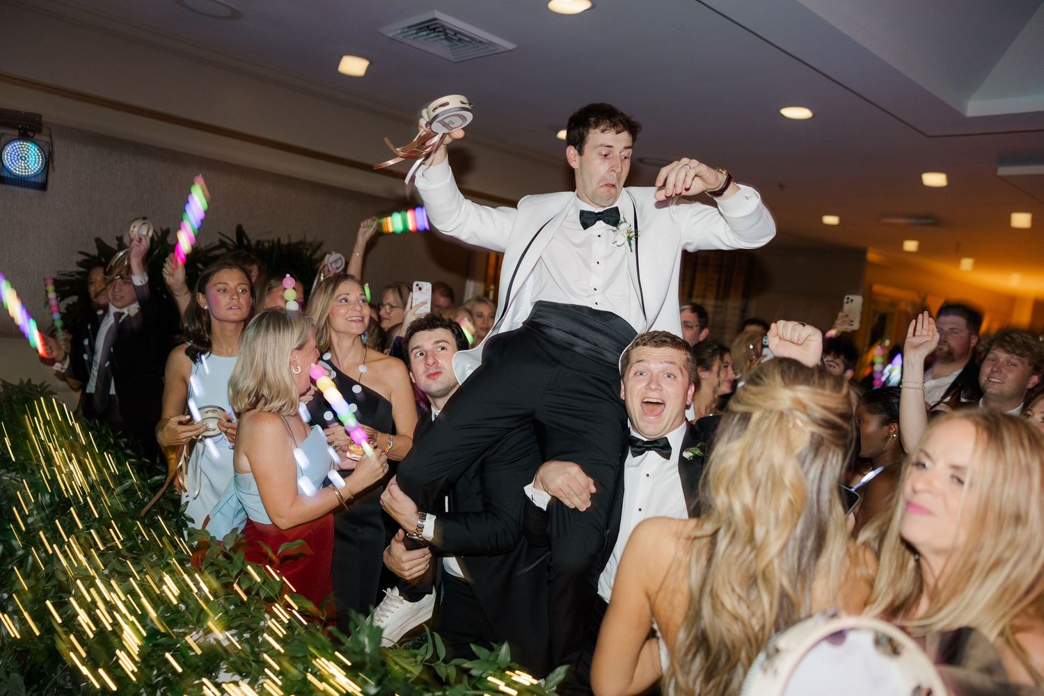 Wedding reception celebration with guests lifting someone in celebration on the dance floor.