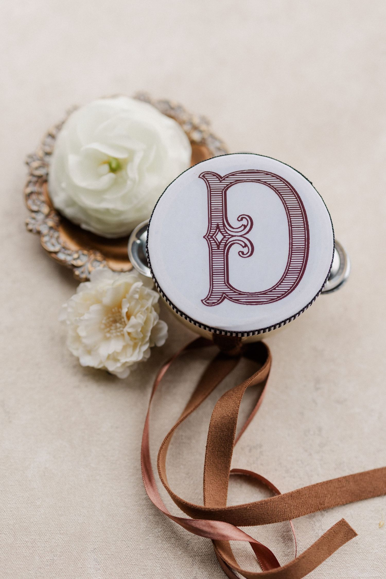 Decorative monogram letter D embellishments with brown ribbon and white floral accents.