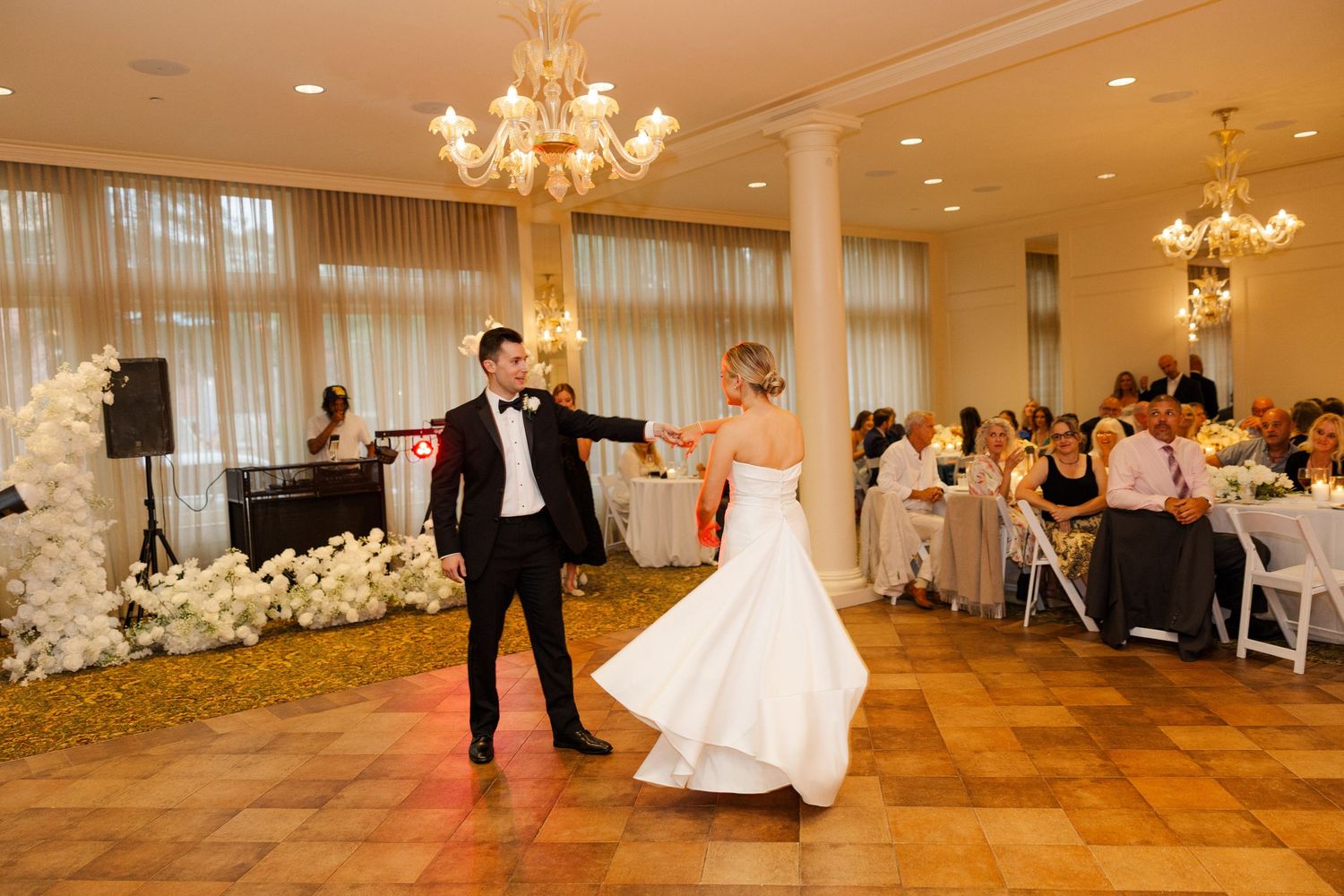 Festive wedding reception dancing captured in a chandelier-lit ballroom.