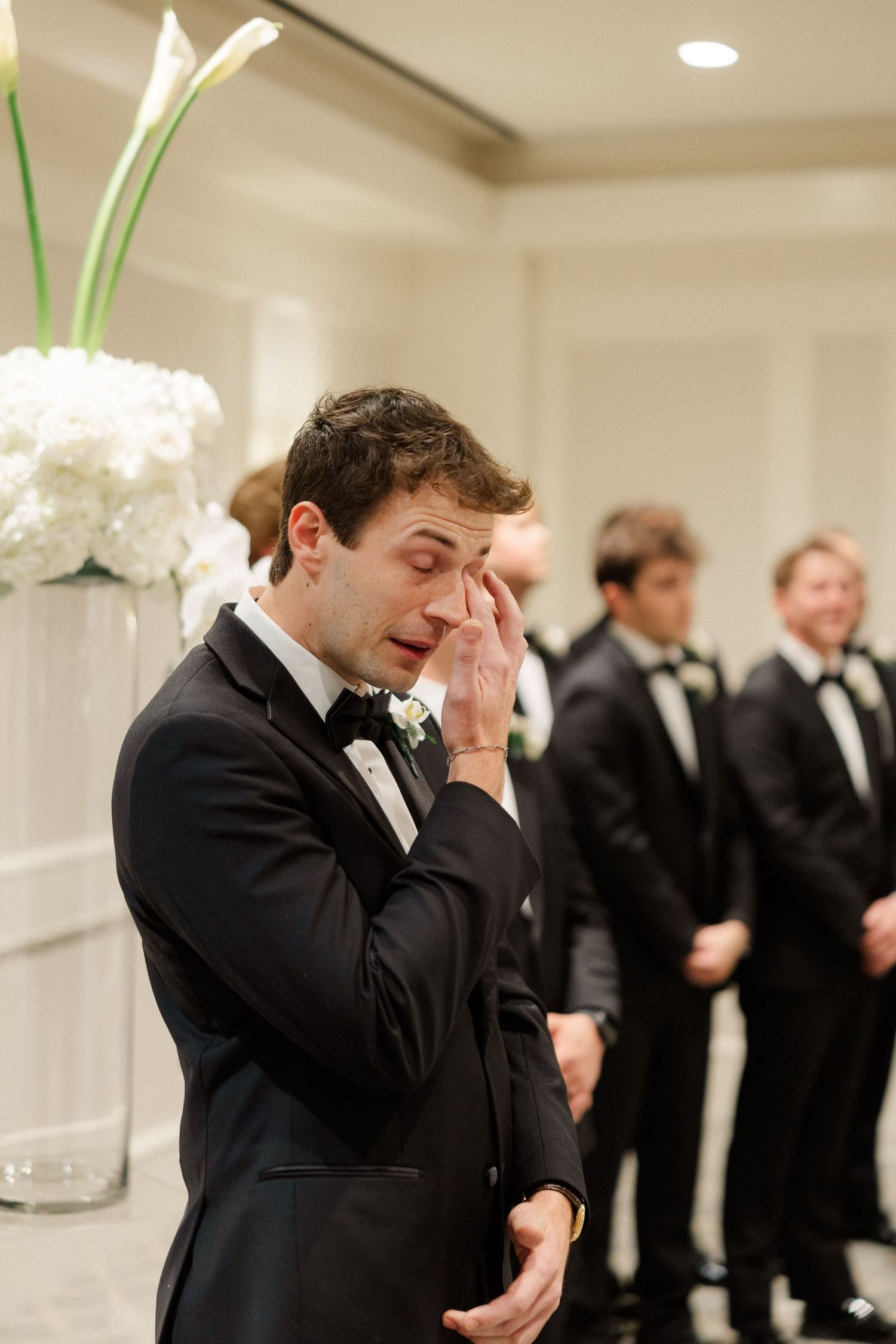 A person in a black tuxedo shows emotional reaction during wedding preparations.