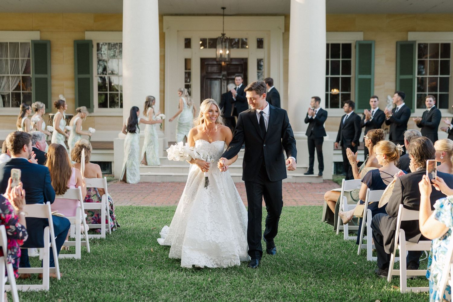 Joyful bride and groom walk back down the aisle after their outdoor ceremony at a classic Southern estate.