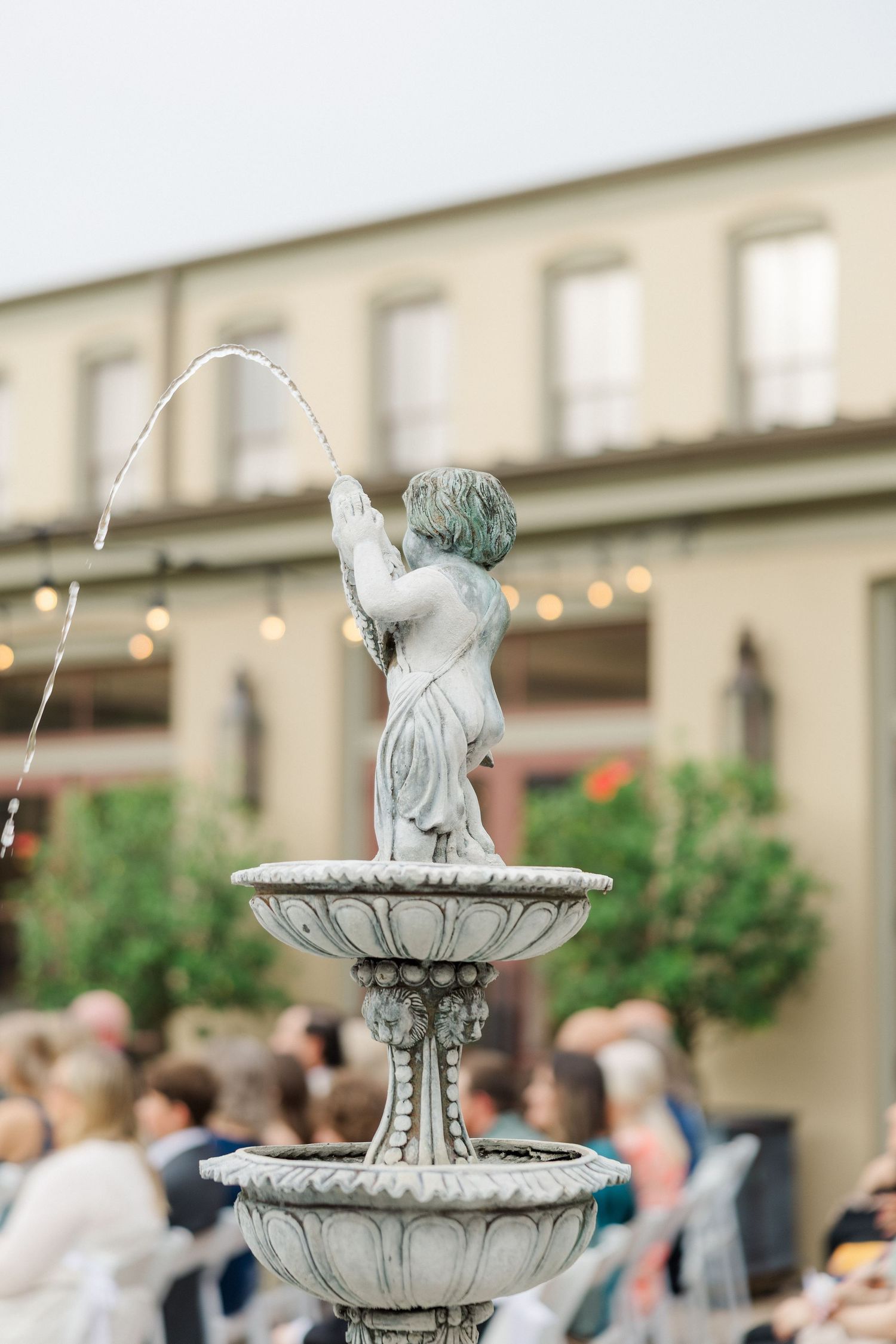 Ornate tiered fountain creates an elegant focal point at an outdoor wedding reception.