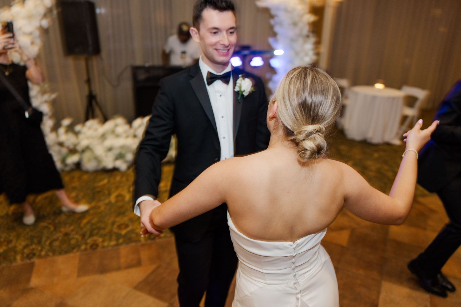 Wedding guests enjoying themselves on the dance floor at an indoor reception.