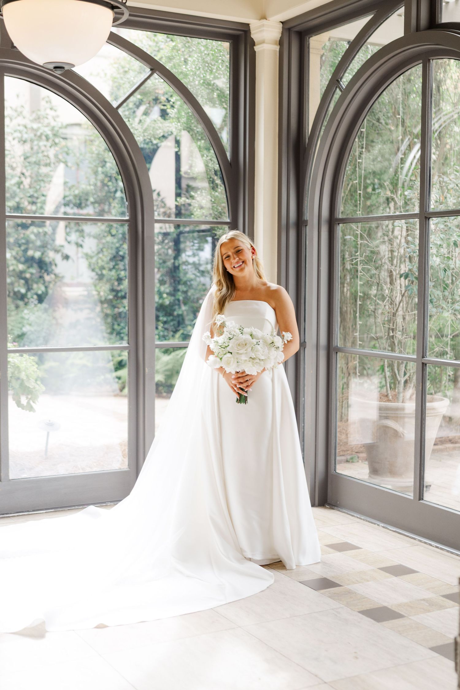 Sunlit bridal portraits in an elegant conservatory with arched windows and natural light.