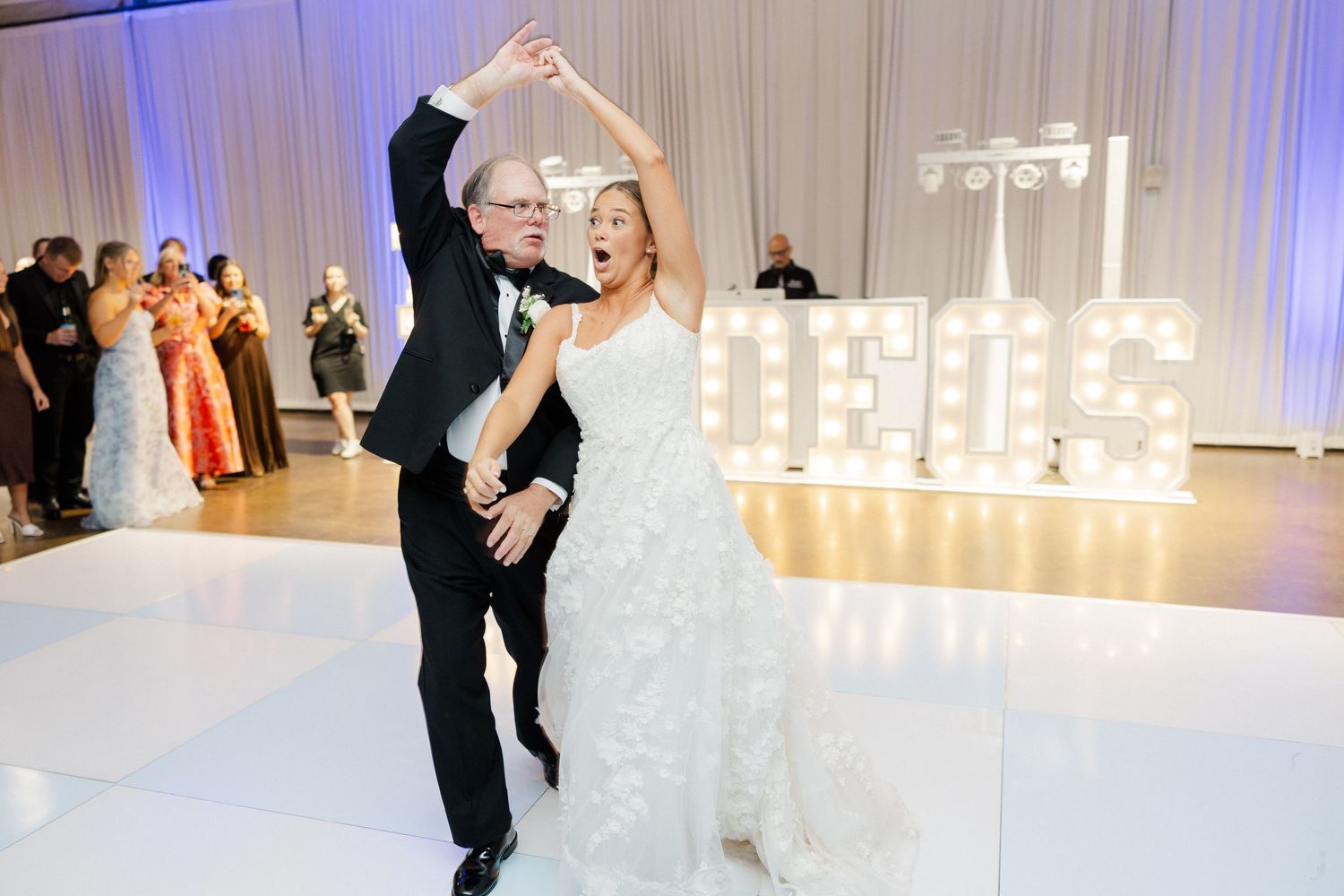 Wedding reception dance floor scene with blue uplighting and illuminated decor.