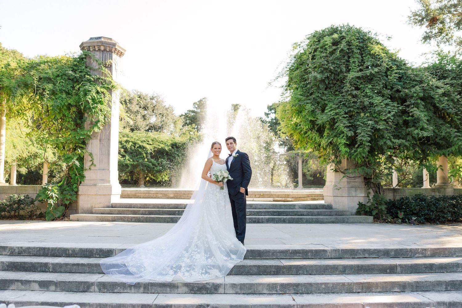 A romantic wedding photoshoot on stone steps with elegant architectural details in the background.