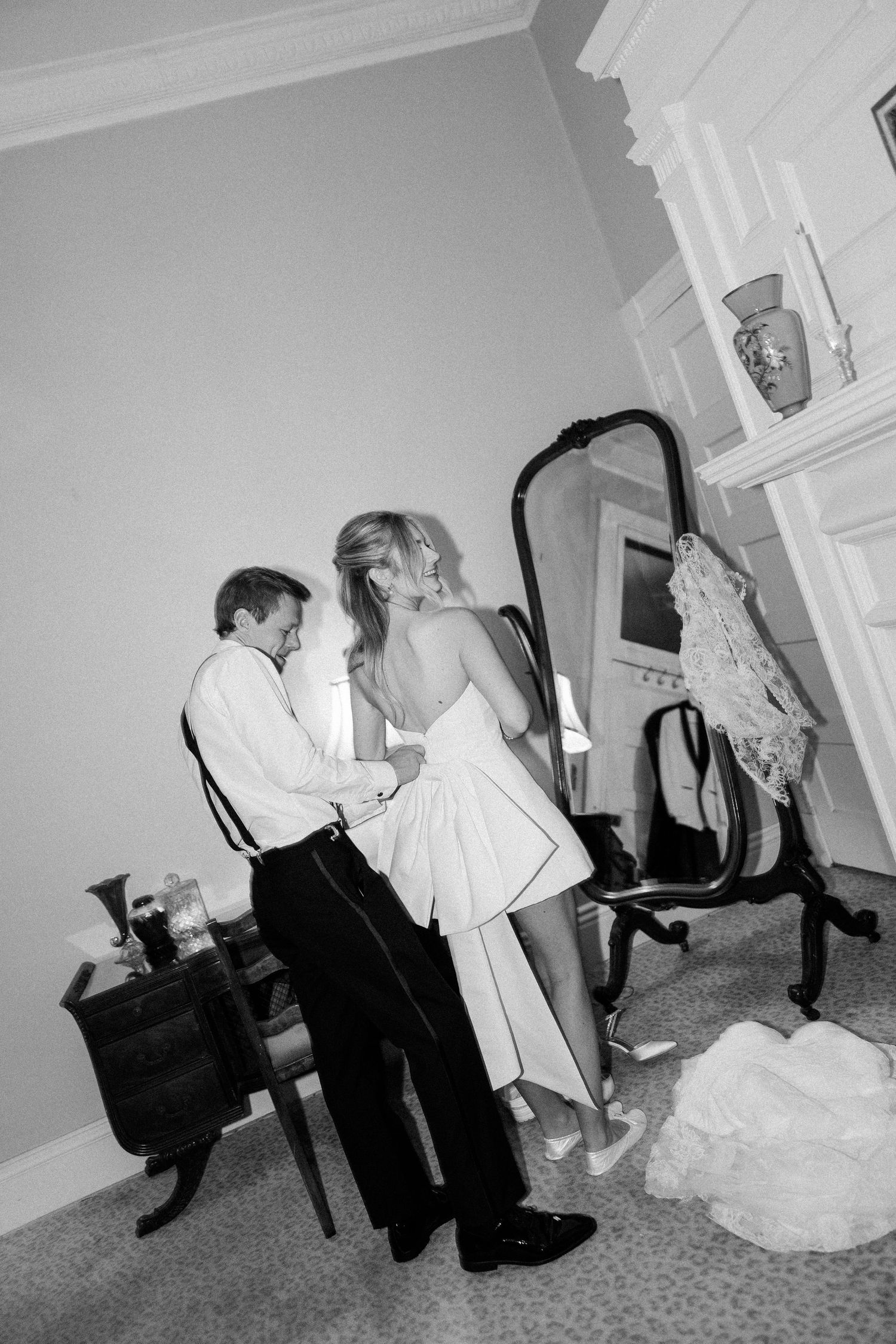 Black and white candid photo of couple dancing in intimate indoor setting.