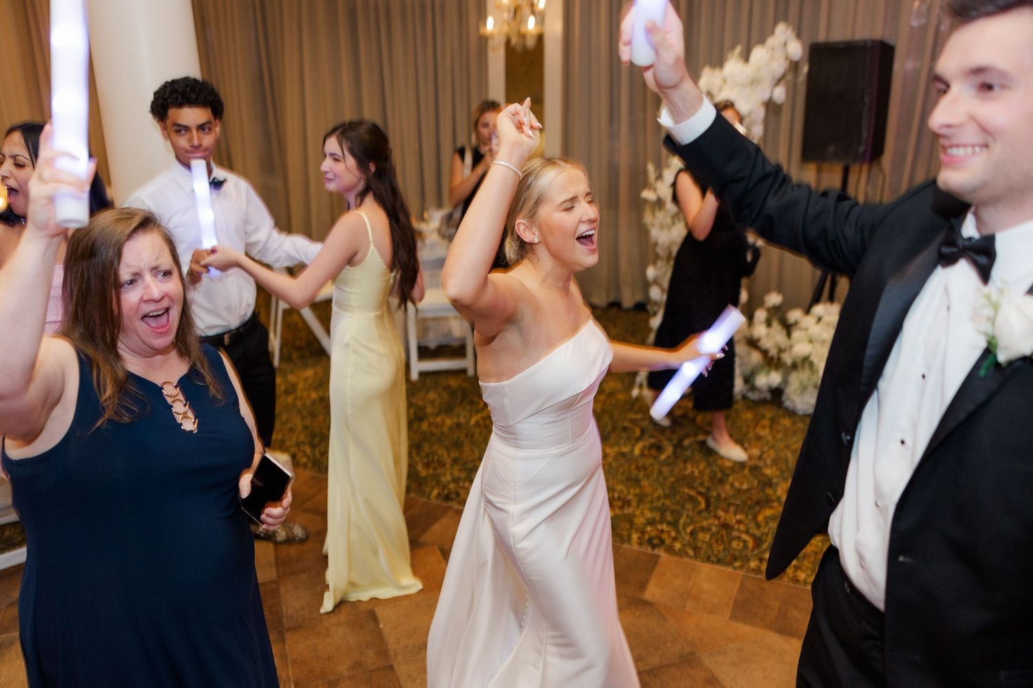 Wedding reception dance floor with guests celebrating and dancing in formal attire.