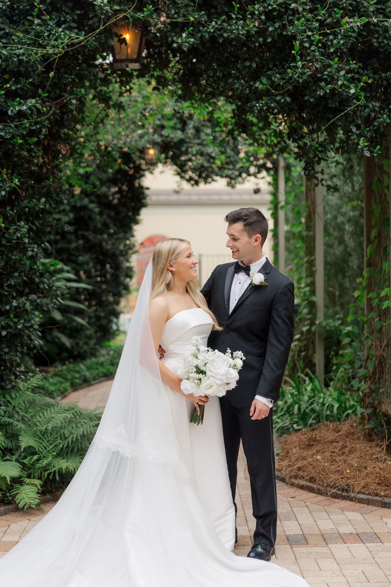 Romantic garden wedding scene with lush greenery and brick pathway.