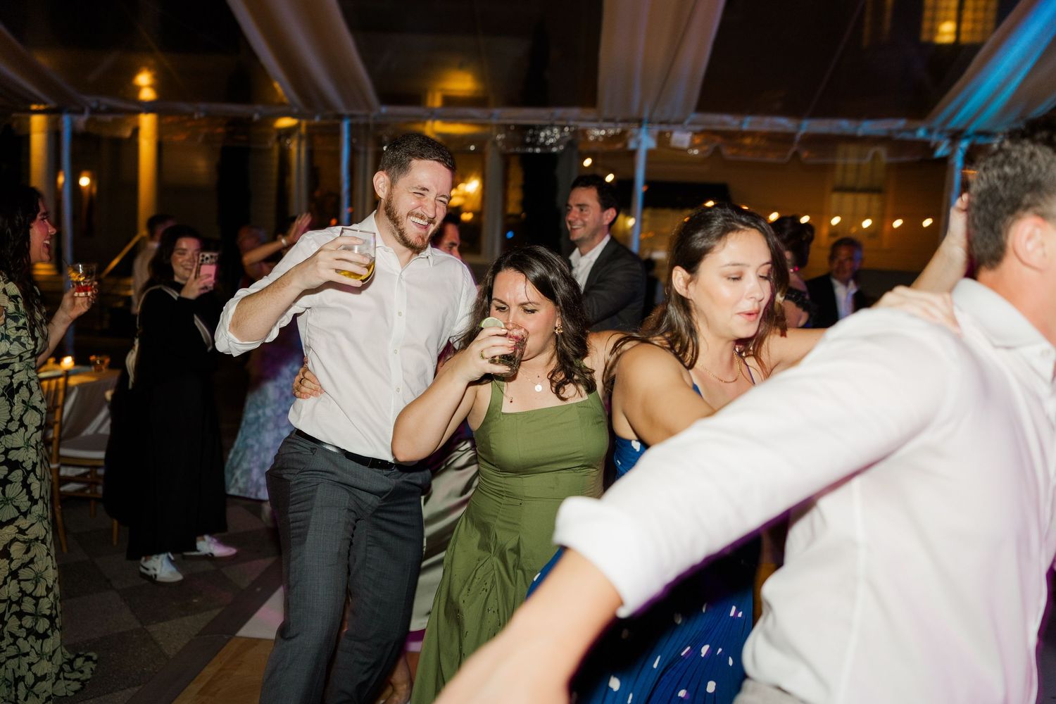 Wedding guests dancing and celebrating at a lively evening reception party.