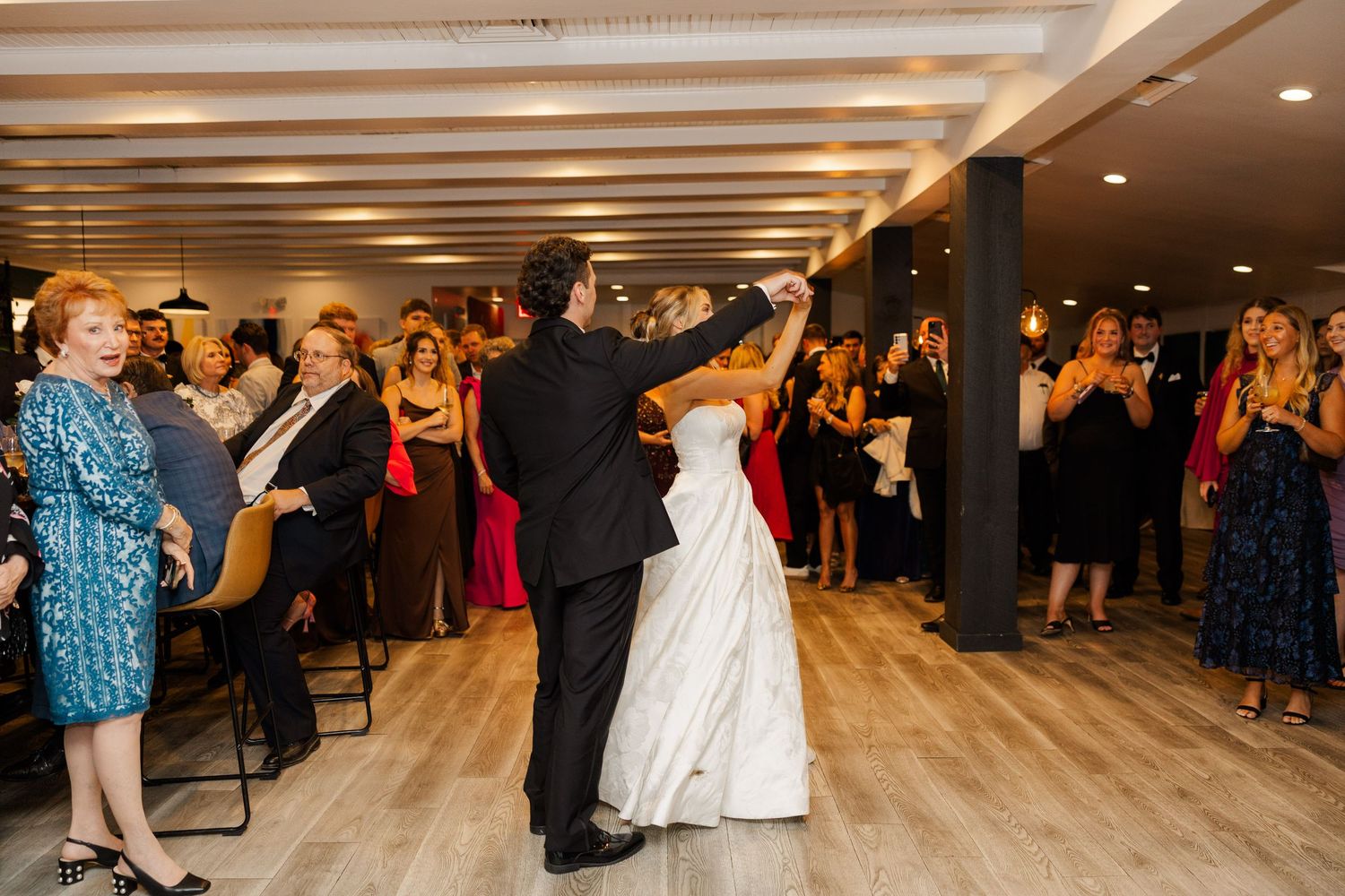 Wedding reception dance party with guests celebrating on a modern wood floor.