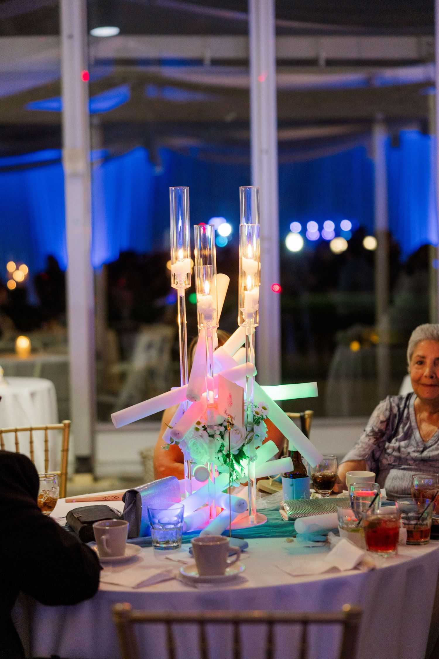 Elegant wedding reception table settings with glowing centerpieces and blue ambient lighting.