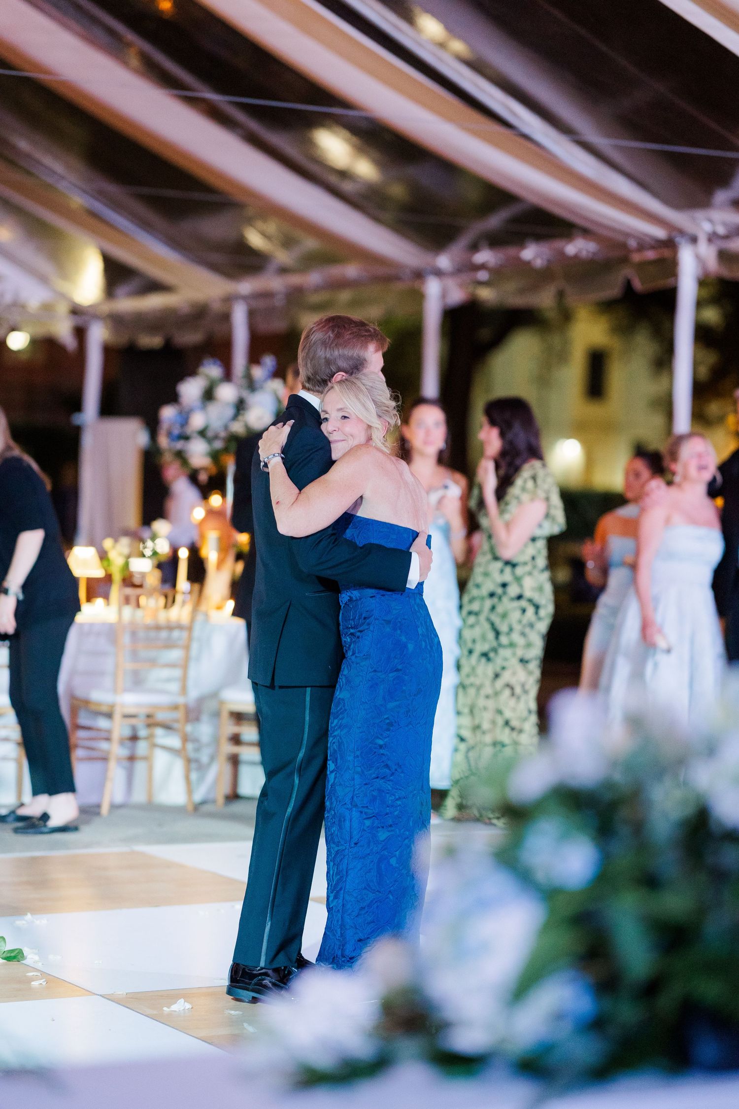 Couple slow dancing at an elegant wedding reception with string lights and floral decorations.