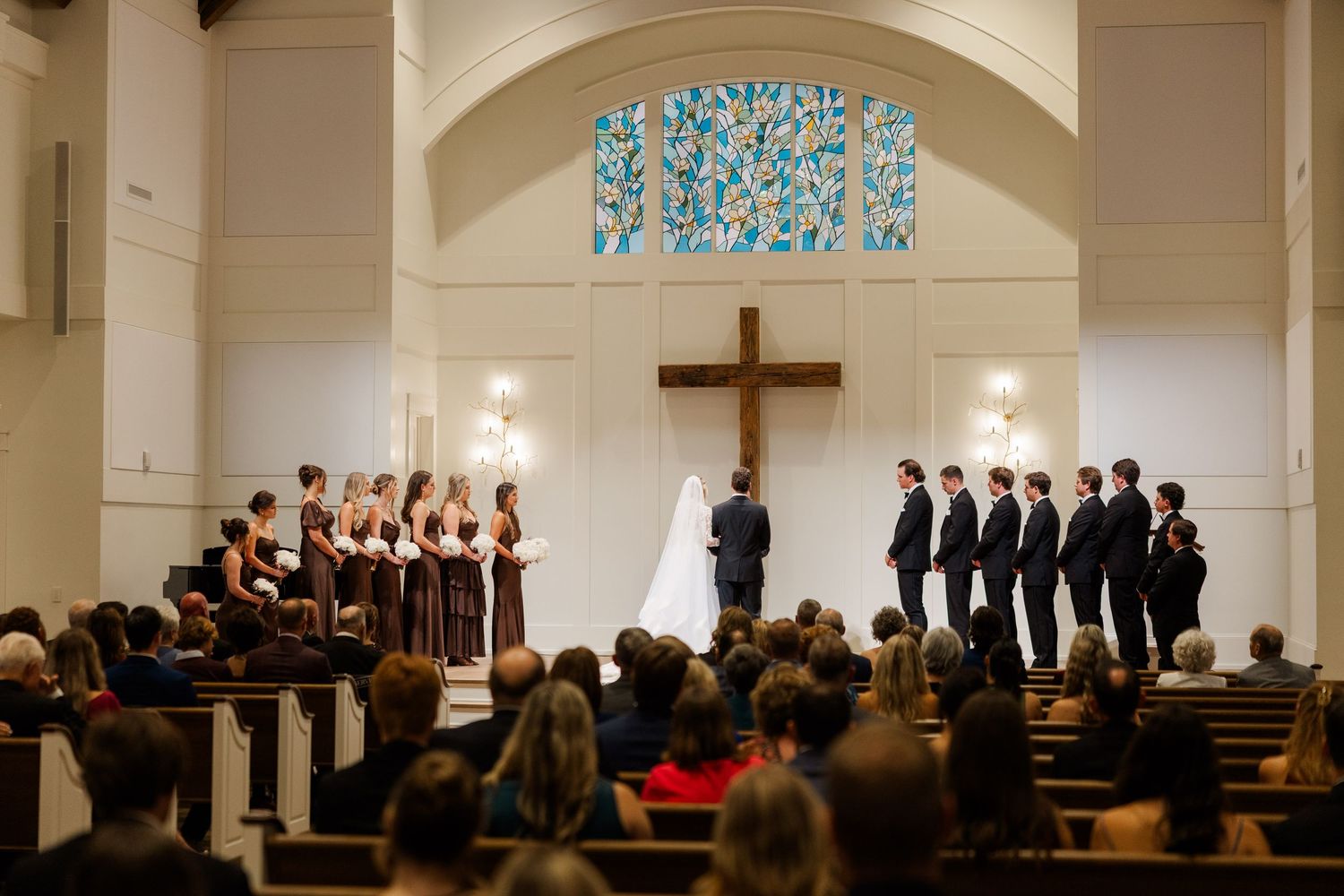 A church wedding ceremony with guests seated and wedding party standing at the altar.
