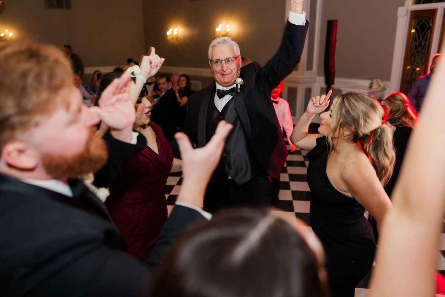 Guests dance and celebrate on a black and white checkered dance floor at an elegant wedding reception.