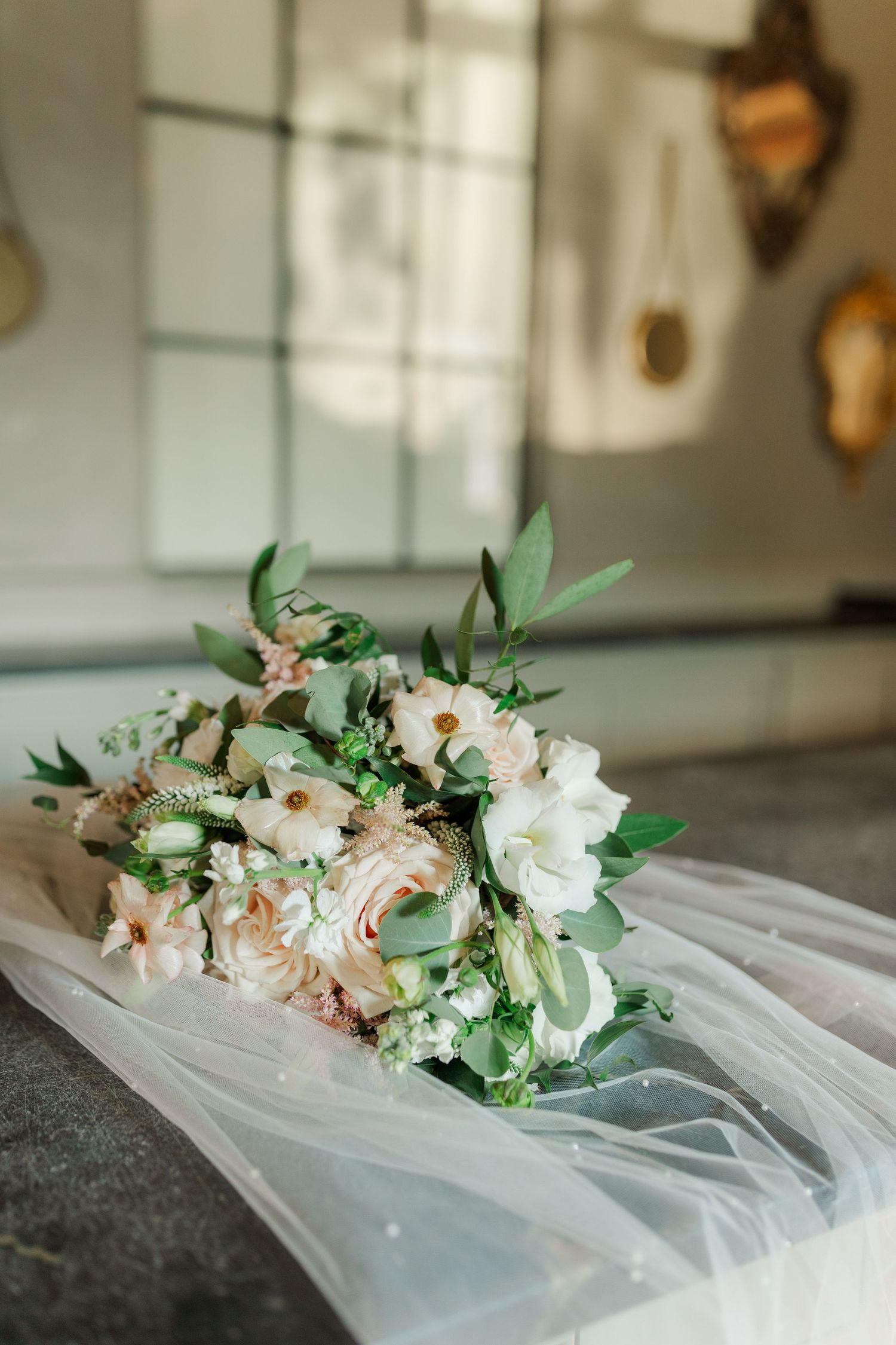Romantic bridal bouquet with white and blush flowers laying on tulle fabric.