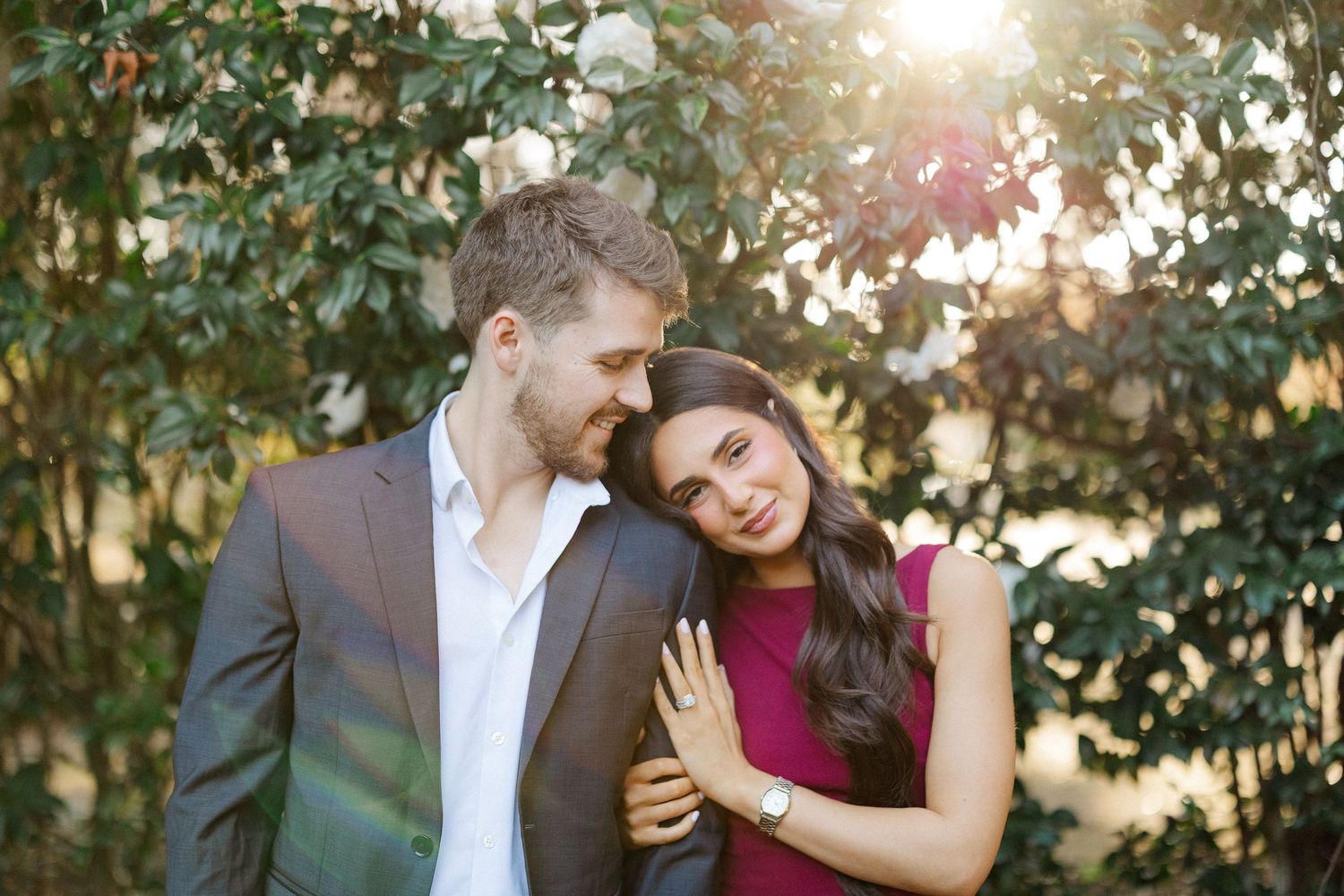 A couple in formal attire shares romantic moments in a garden setting during golden hour sunset.